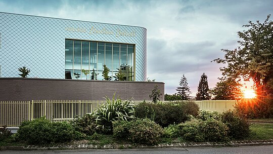 Le collège Léontine Dolivet, à Cesson-Sévigné, se distingue par sa façade en aluminium remarquable, composée d'environ 15 000 losanges PREFA argent métallisé. Sa surface chatoyante reflète la lumière, créant une allure à la fois dynamique et élégante. De larges baies vitrées offrent des vues imprenables sur la verdure environnante, tandis que le système de façade PREFA, robuste et durable, garantit une excellente résistance aux intempéries. L'alliance du métal irisé et des lignes architecturales épurées fait de ce bâtiment un véritable chef-d'œuvre et met en valeur les atouts de l'aluminium : légèreté, absence d'entretien et durabilité.