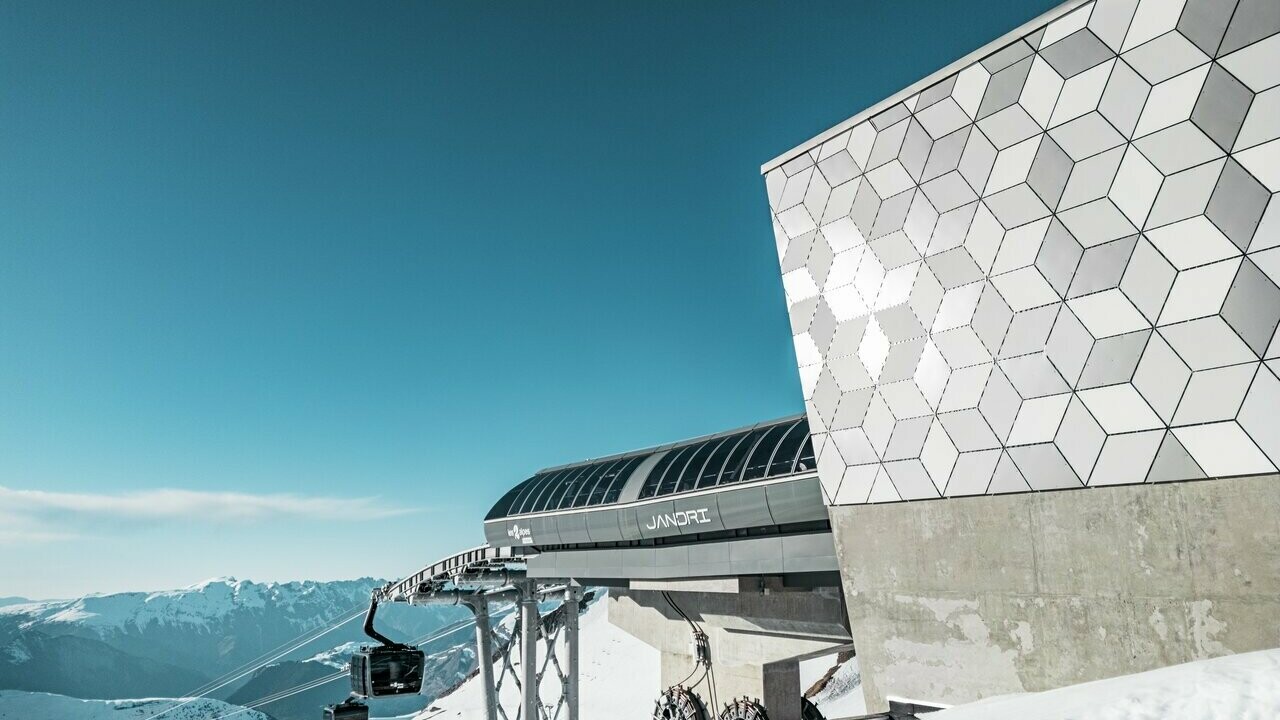 Vue rapprochée de la façade d'une station du nouveau téléphérique Le Jandri de la station Les 2 Alpes, recouverte de panneaux composites en aluminium PREFABOND façonné en losanges de trois couleurs différentes : blanc Prefa, blanc pur et argent fumé.