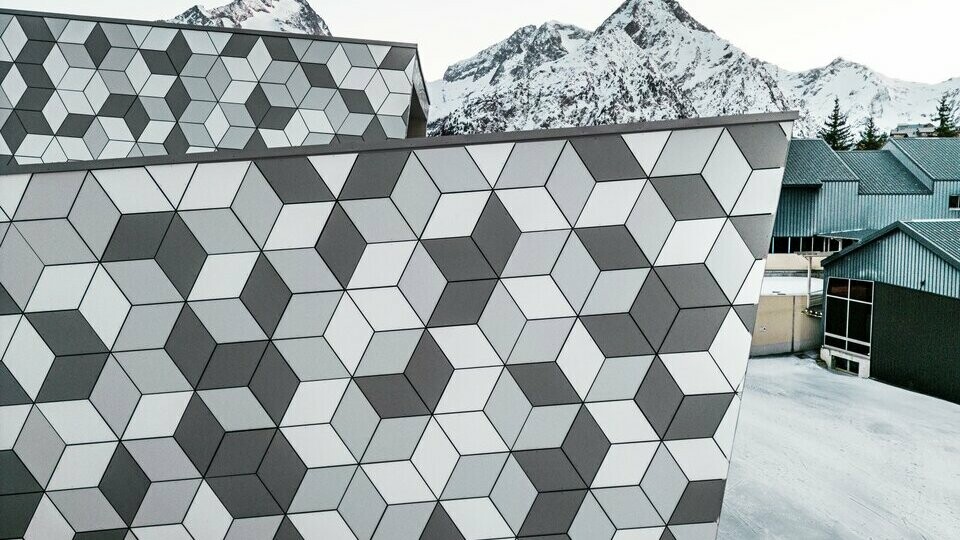 Zoom sur la station du nouveau téléphérique Le Jandri de la station Les 2 Alpes, recouverte de panneaux composites en aluminium PREFABOND façonné en losanges de trois couleurs différentes : blanc Prefa, blanc pur et argent fumé.
