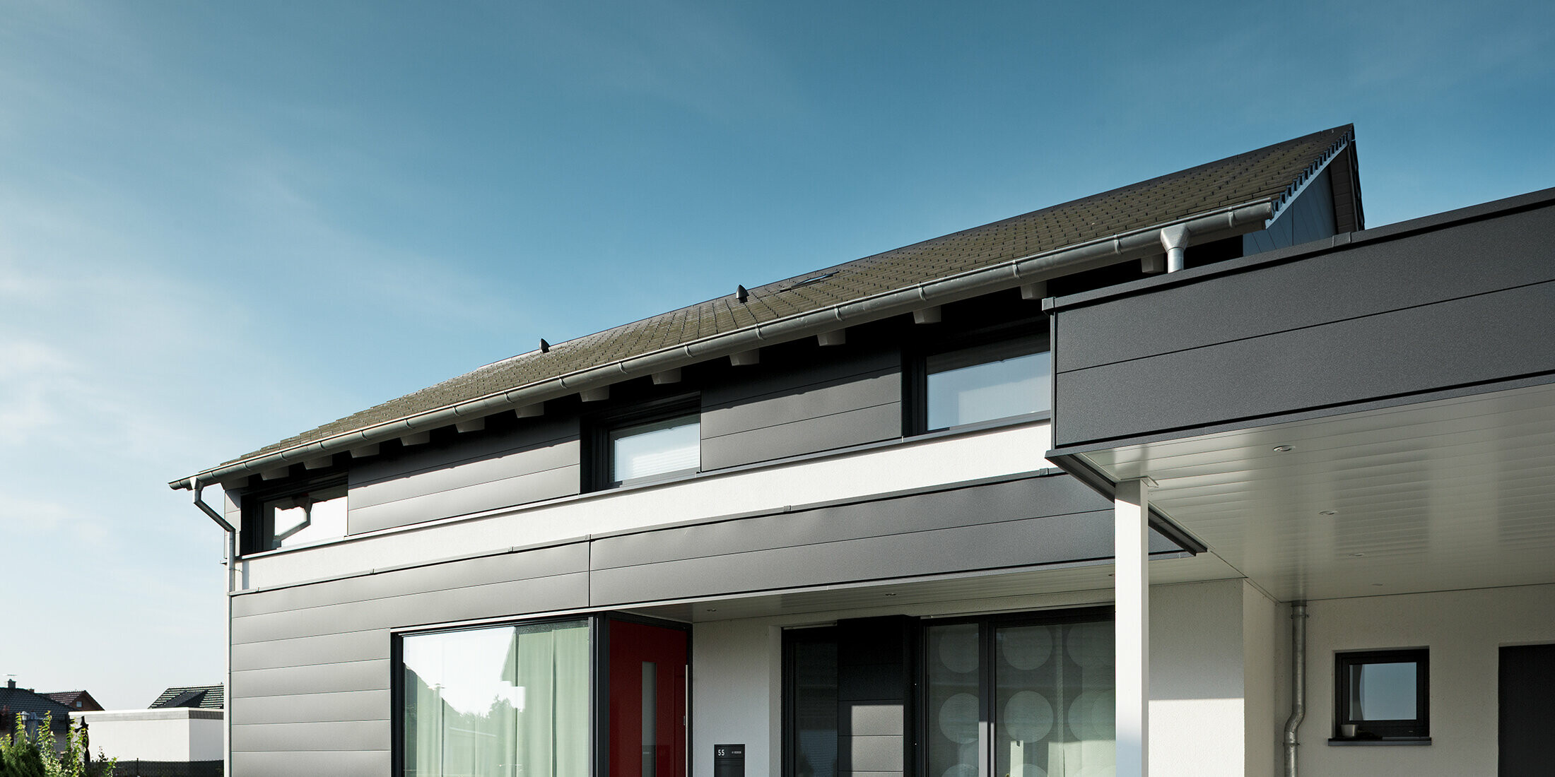 Rückseite eines modernen Einfamilienhauses in Isenbüttel, ausgestattet mit PREFA Aluminium-Sidings in P.10 Anthrazit – ein perfektes Zusammenspiel von Funktionalität und Ästhetik. Die großzügigen Fenster sorgen für ein optisches Highlight und lichtdurchflutete Innenräume.
