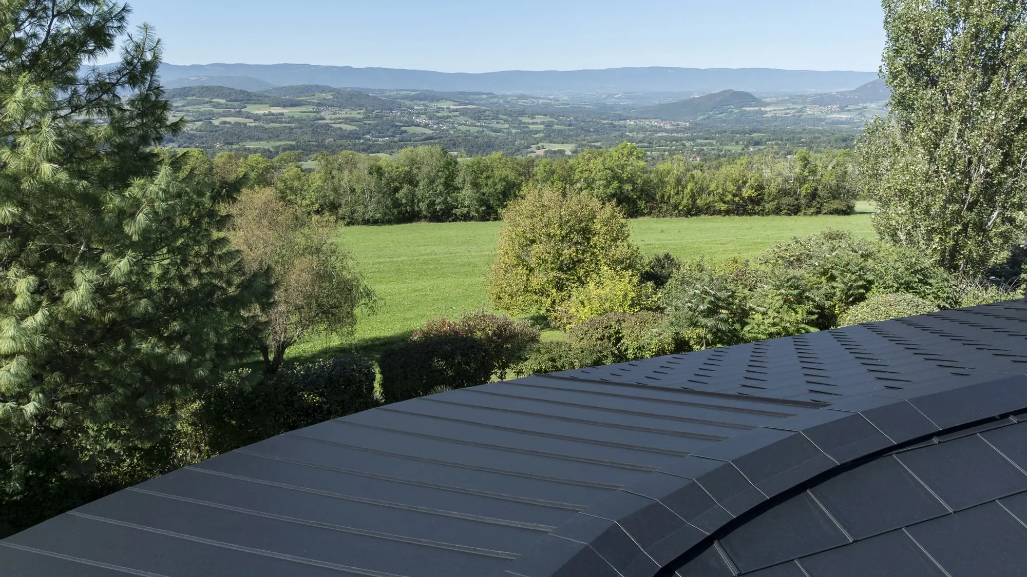 Photo du haut du toit où on distingue clairement le côté courbé et arrondi de la toiture. Un défi technique relevé grâce aux produits PREFA et à la flexibilité de l'aluminium.