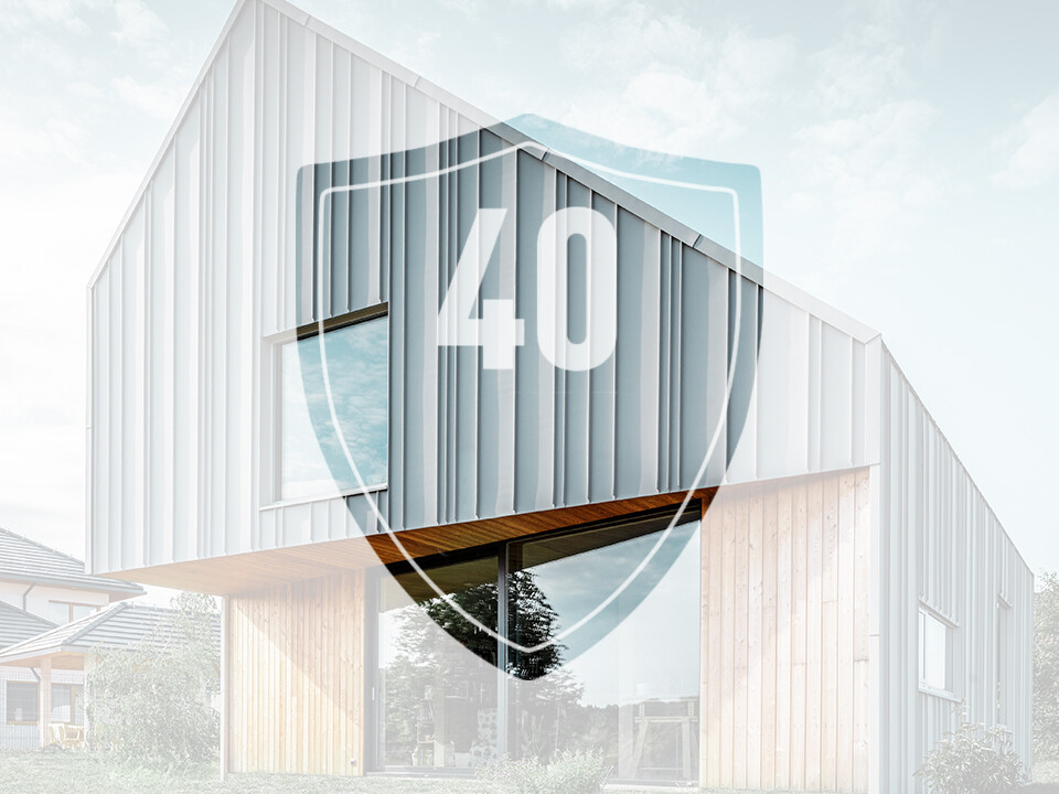 La photo montre un panneau avec le chiffre « 40 », qui représente la garantie des produits en aluminium PREFA, devant une maison individuelle moderne.