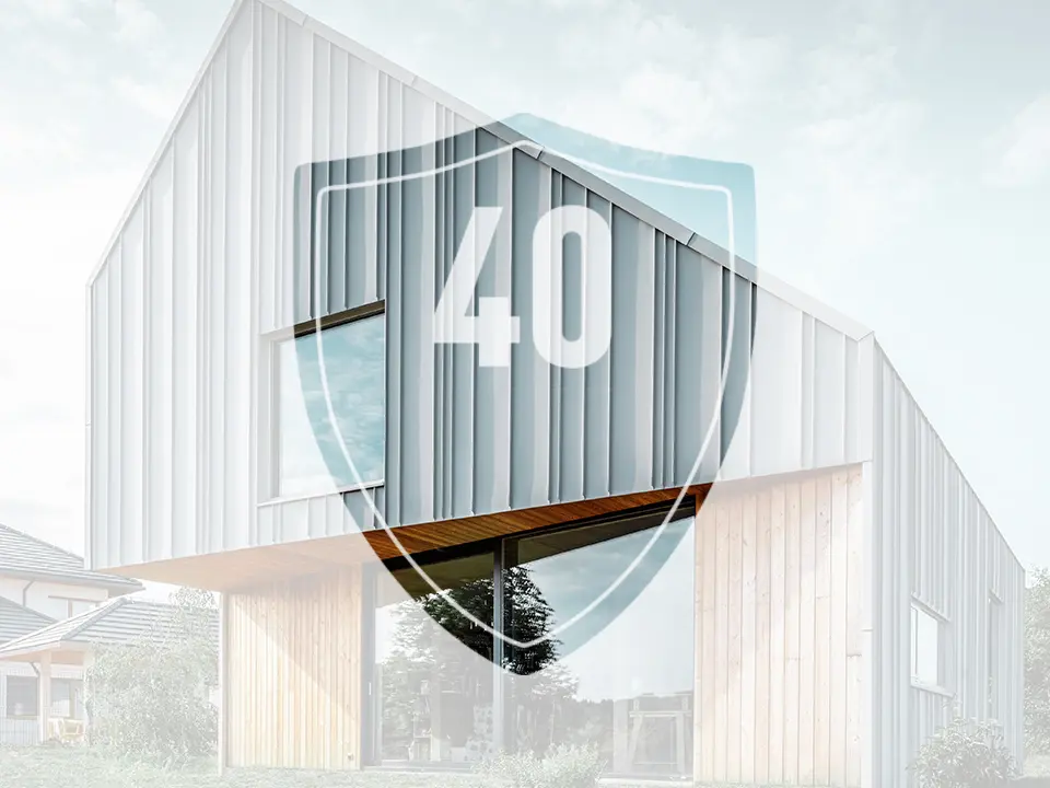 La photo montre un panneau avec le chiffre « 40 », qui représente la garantie des produits en aluminium PREFA, devant une maison individuelle moderne.