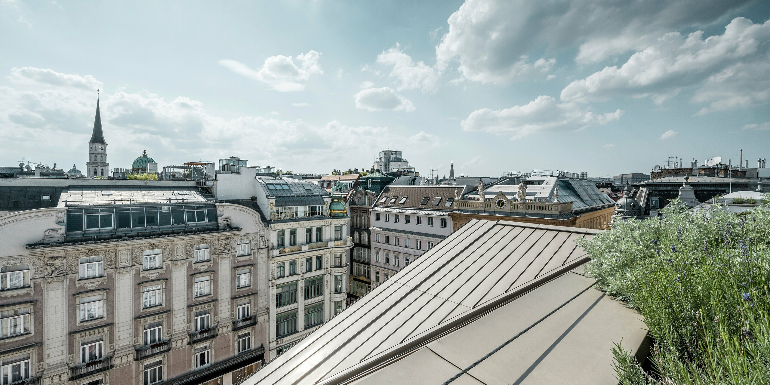 Vue large sur les toits de Vienne, avec à gauche les bandes Prefalz à l’élégante couleur bronze de l’hôtel Rosewood Vienna.