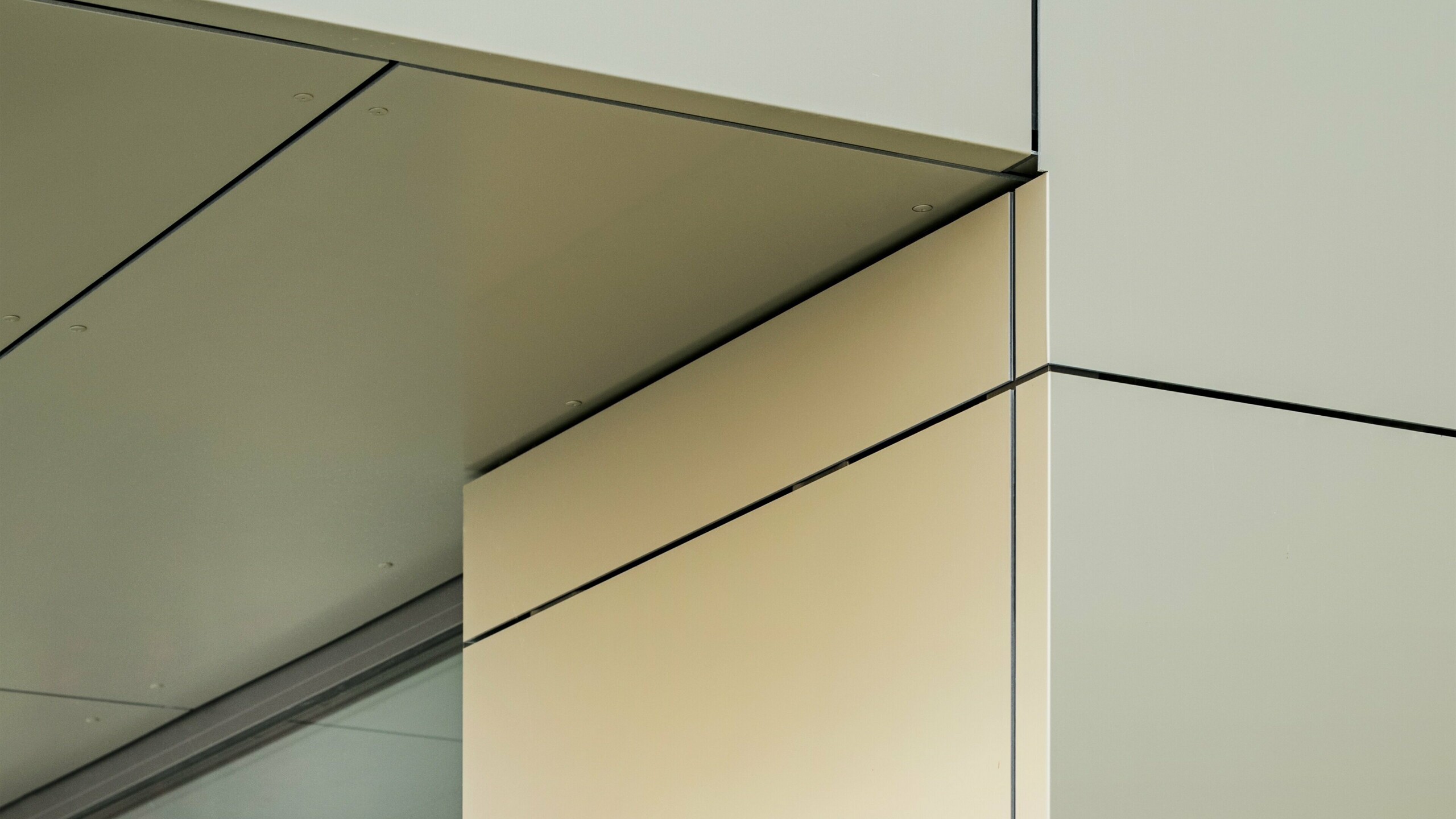 Détail de la façade de la mairie d'Alzenau, qui montre la précision des arêtes et des transitions des panneaux composites en aluminium PREFA, ici dans la couleur bronze. Les panneaux sont parfaitement assemblés, créant ainsi des lignes claires et modernes. La brillance métallique des panneaux est soulignée par les lignes fines des joints et les détails minimalistes de l'architecture, ce qui confère à la façade un aspect élégant et contemporain.