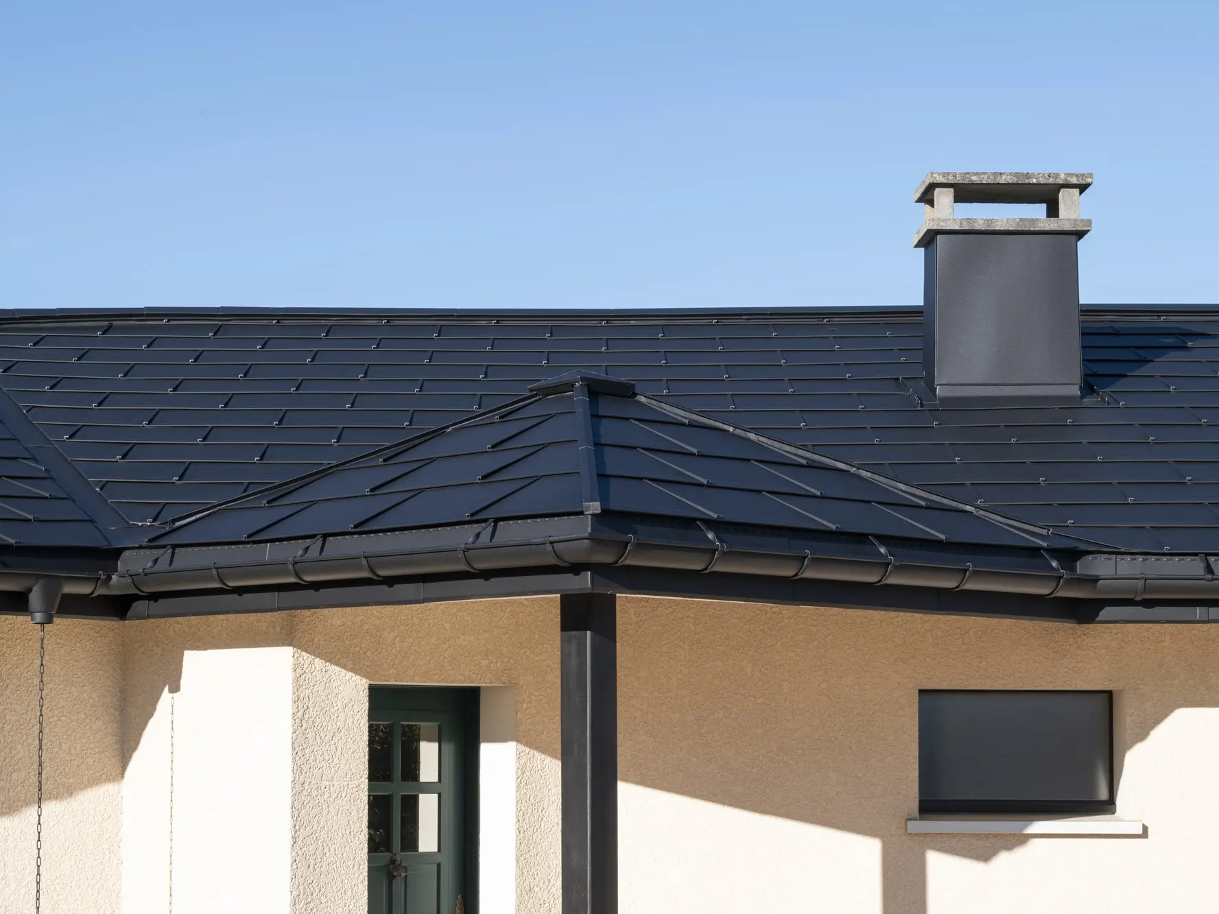 Photo rapprochée de l'ensemble de la maison rénovée grâce aux produits en aluminium PREFA : R.16, joint debout Prefalz et gouttière demi-ronde, le tout en P.10 noir pour une impression d'homogénéité