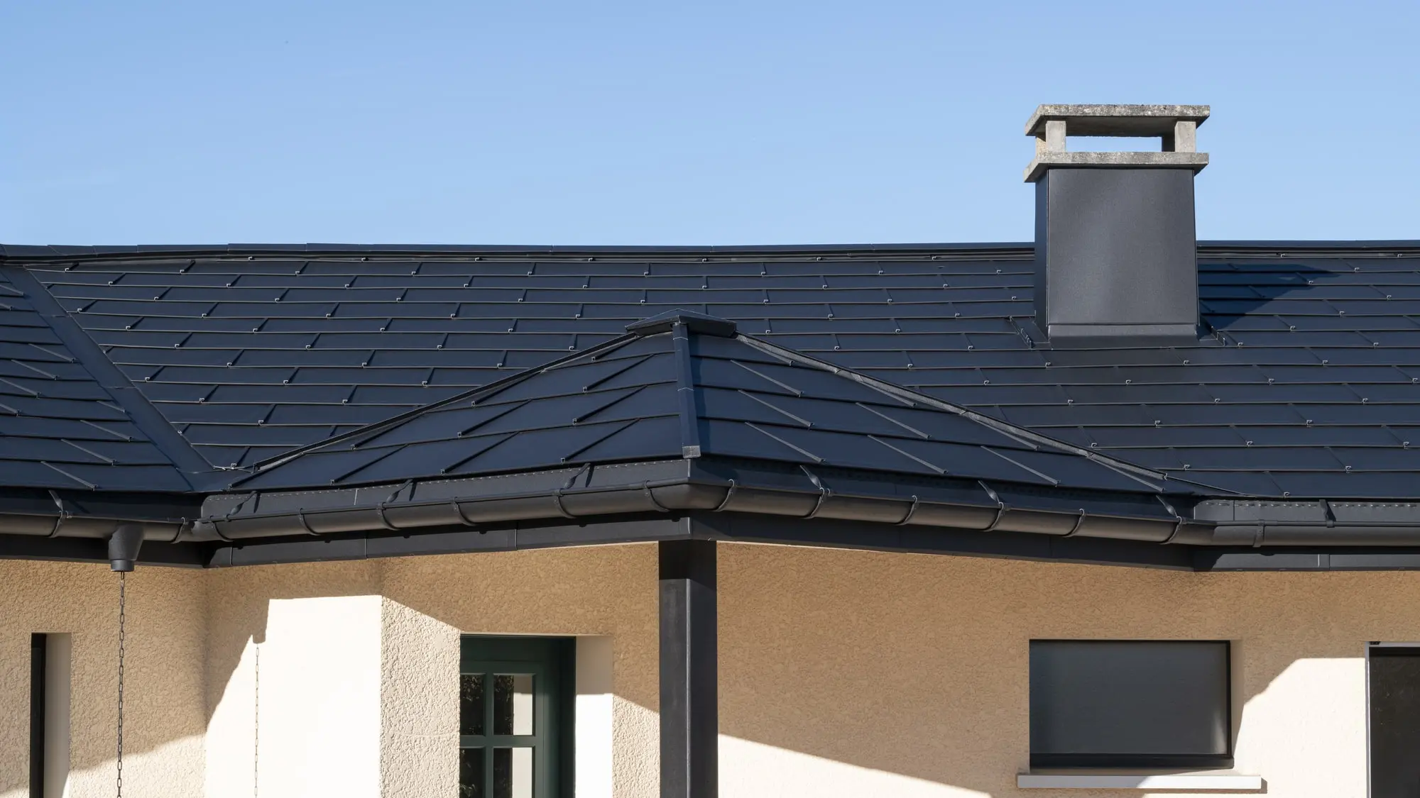 Photo rapprochée de l'ensemble de la maison rénovée grâce aux produits en aluminium PREFA : R.16, joint debout Prefalz et gouttière demi-ronde, le tout en P.10 noir pour une impression d'homogénéité