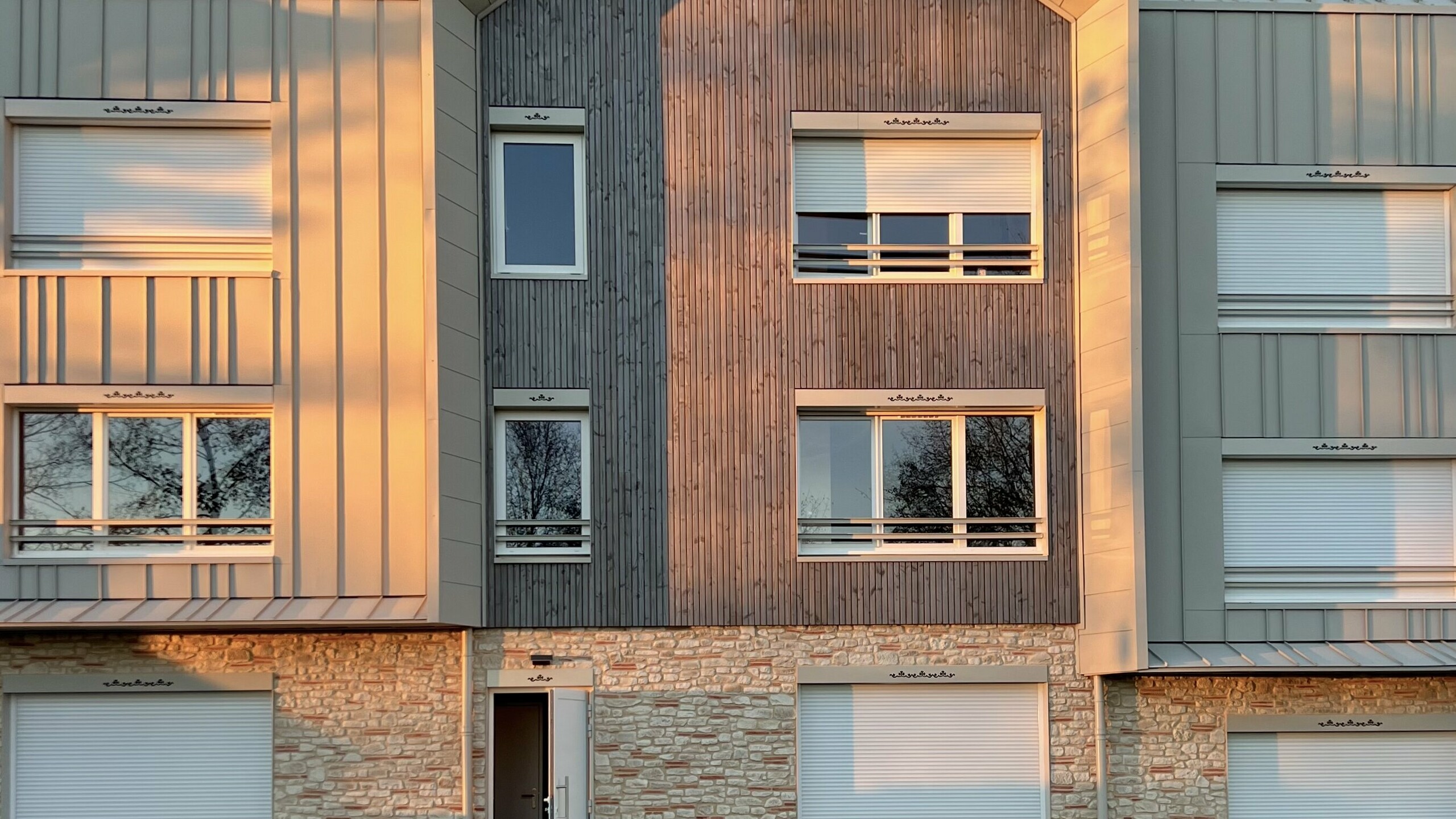 Prise de vue de face du complexe résidentiel attenant au Château des Avenières dont la façade et la toiture sont couvertes de joint debout PREFALZ dans la teinte spéciale Dune.