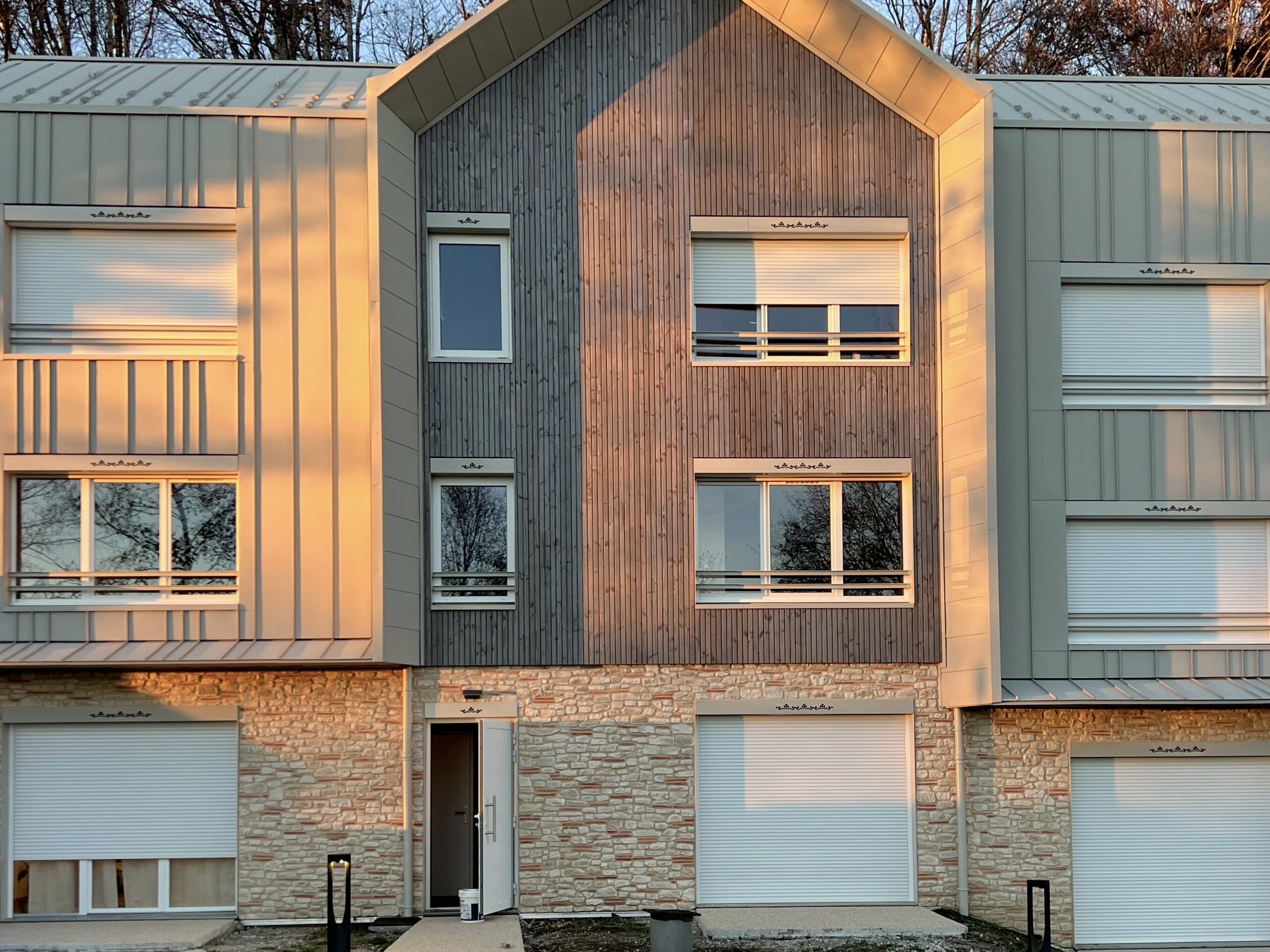 Prise de vue de face du complexe résidentiel attenant au Château des Avenières dont la façade et la toiture sont couvertes de joint debout PREFALZ dans la teinte spéciale Dune.
