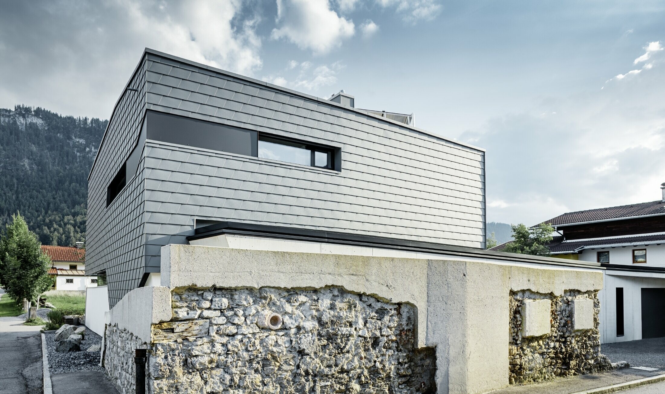 Maison individuelle moderne au toit plat avec de grandes baies vitrées — Façade réalisée avec des bardeaux PREFA en aluminium de couleur gris souris