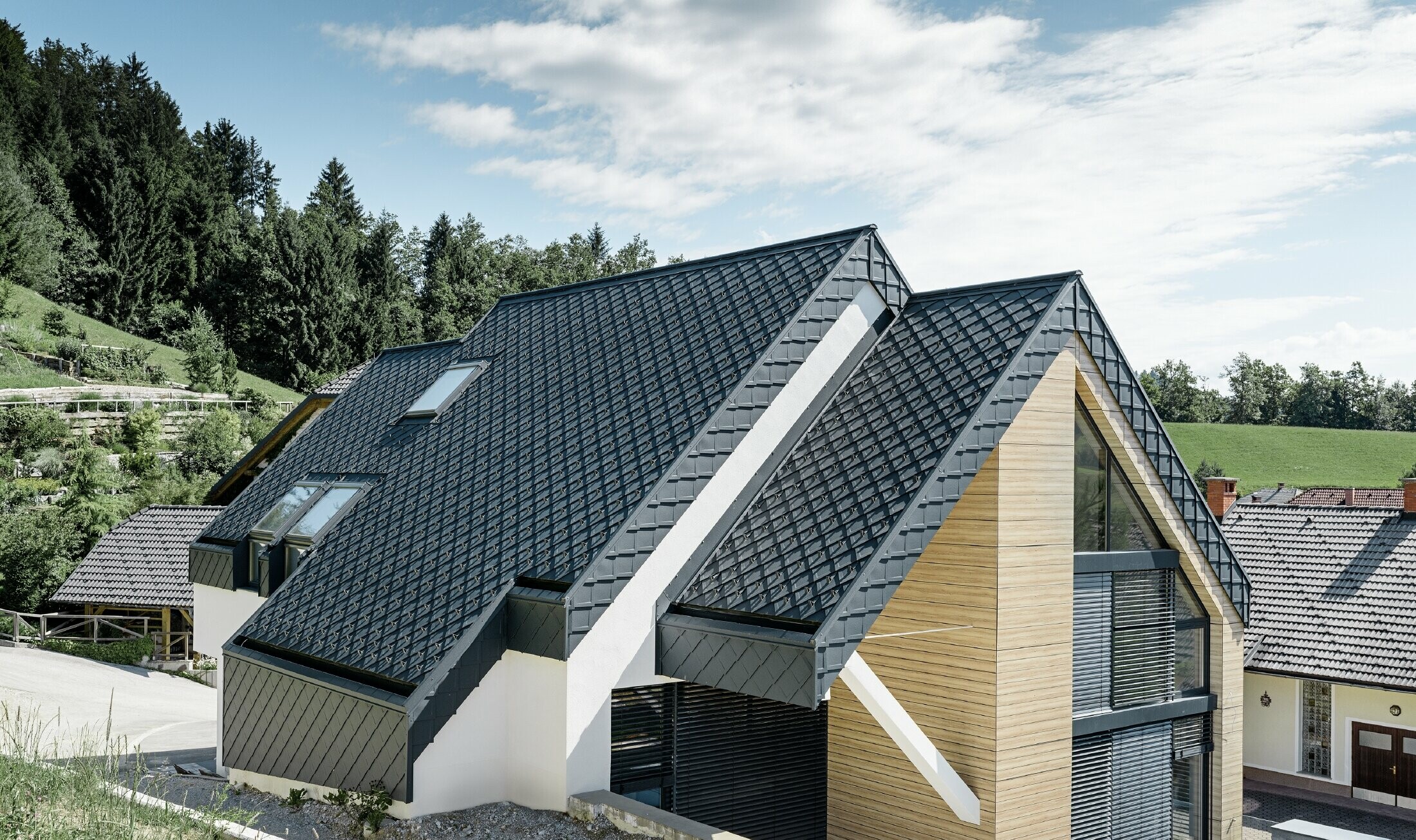 Maison individuelle avec toit à deux versants sans saillie, avec façade imitation bois et toit en aluminium couleur anthracite