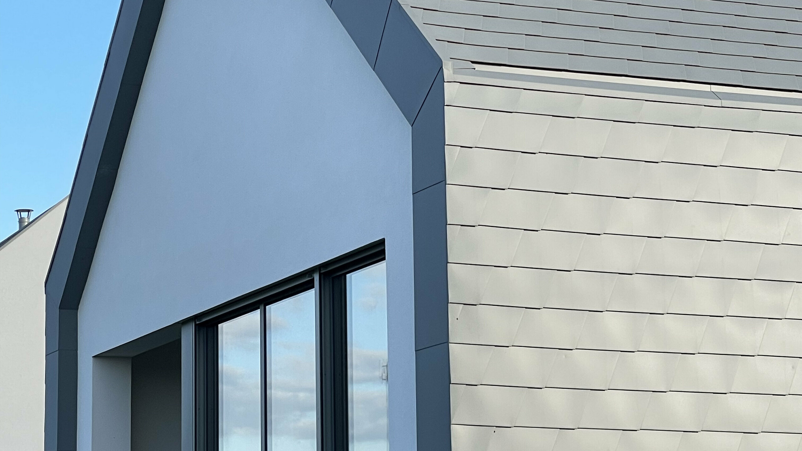 Vue de côté de cette maison contemporaine de Niederhausbergen. On voit la manière dont la toiture continue vers la façade et la netteté de l'angle et des rives.