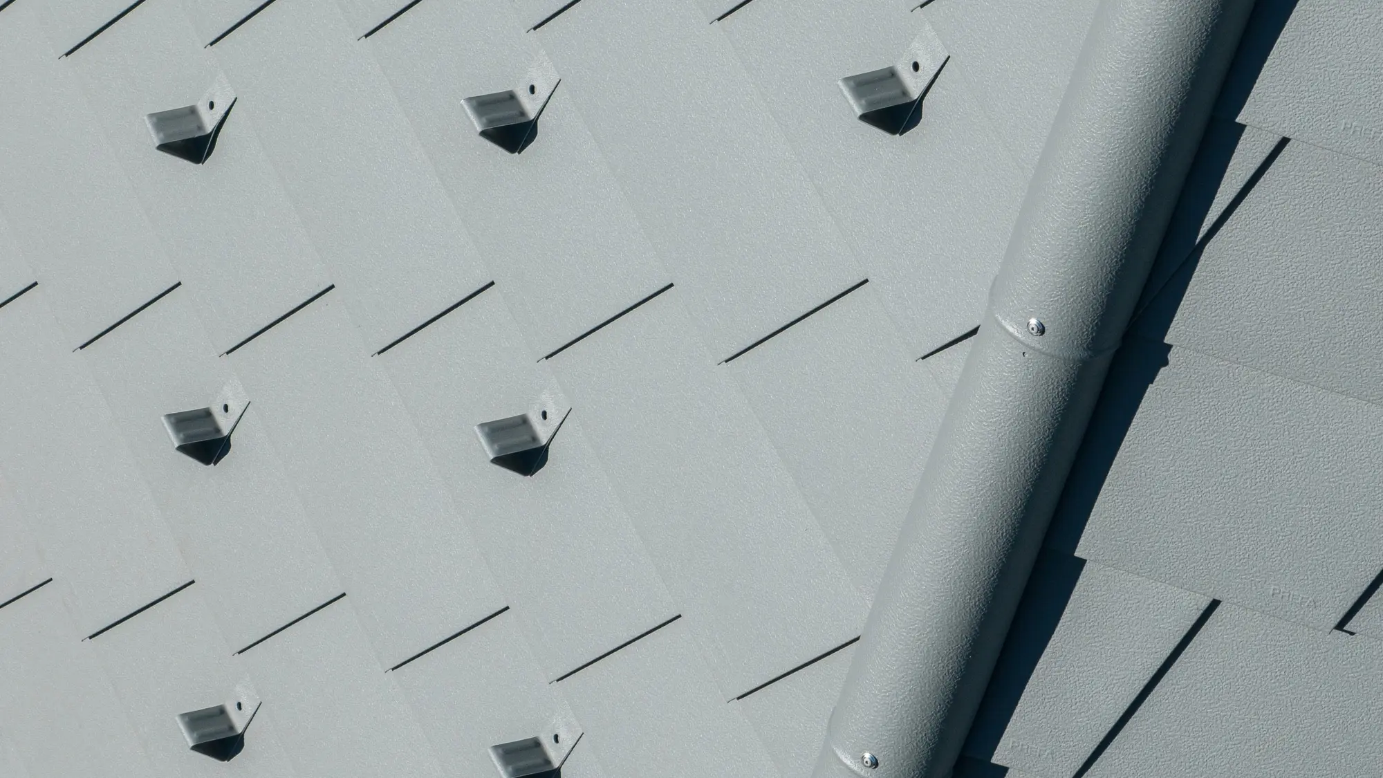 Zoom sur le faitage et les bardeaux de toiture PREFA dans la teinte P.10 gris souris stucco