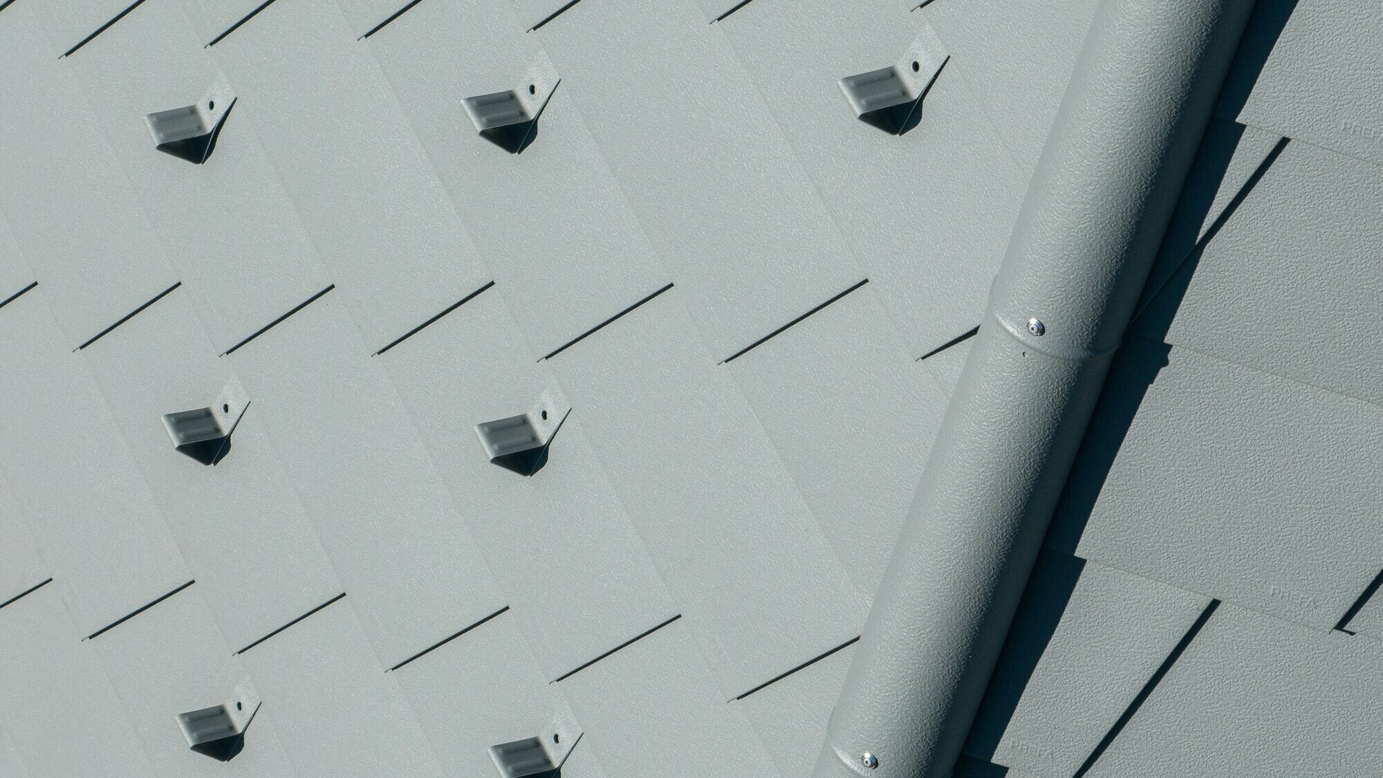 Zoom sur le faitage et les bardeaux de toiture PREFA dans la teinte P.10 gris souris stucco