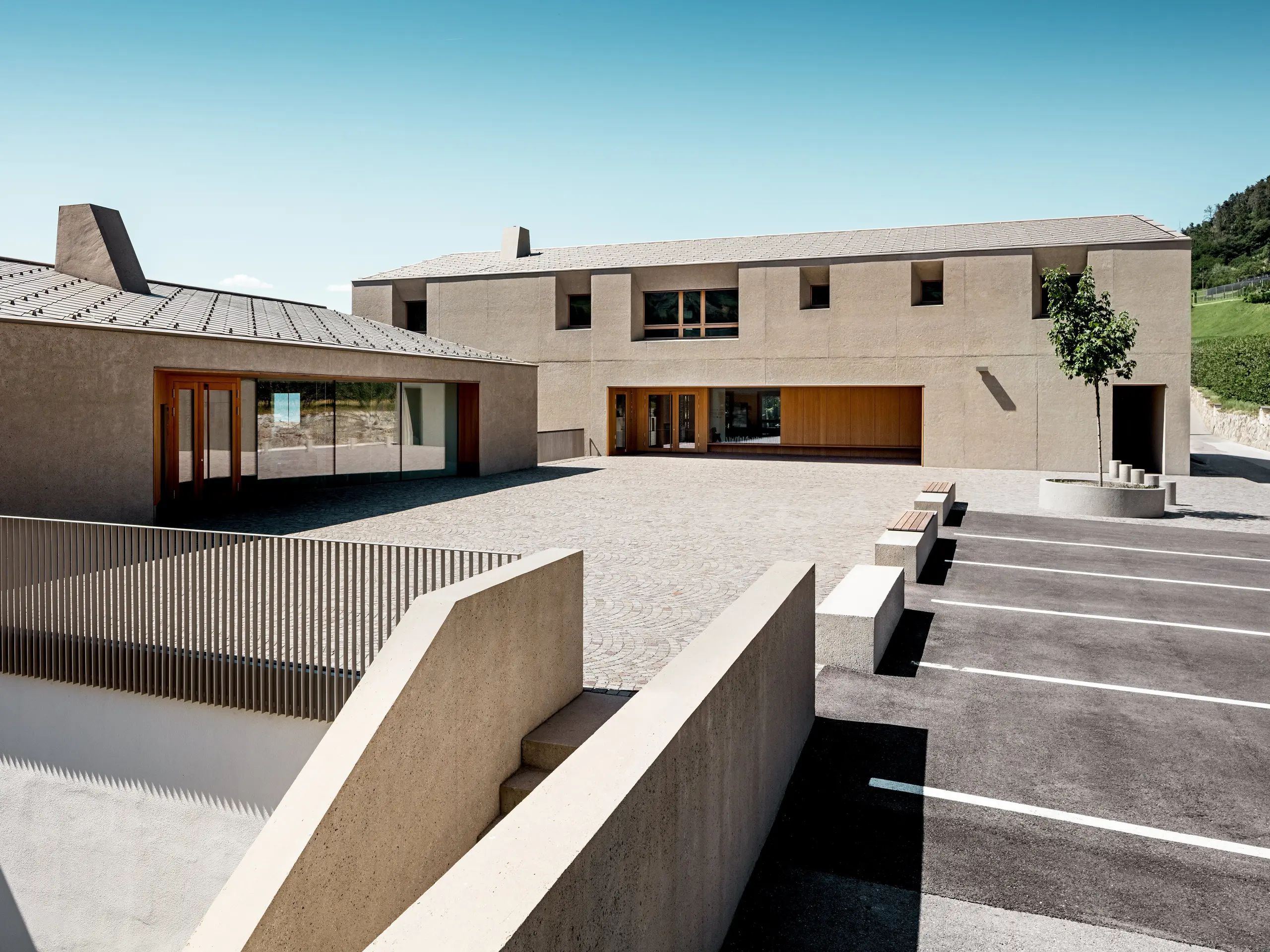 Le centre éducatif de Riffian, dans le Tyrol du Sud, allie architecture moderne et conception soignée de la toiture. Les deux volumes, dotés de losanges de toiture PREFA 44 × 44 en finition P.10 Bronze, s'intègrent harmonieusement dans le paysage. Ce revêtement en aluminium, d'une grande durabilité, assure une protection fiable contre les intempéries tout en soulignant les lignes épurées du bâtiment scolaire.