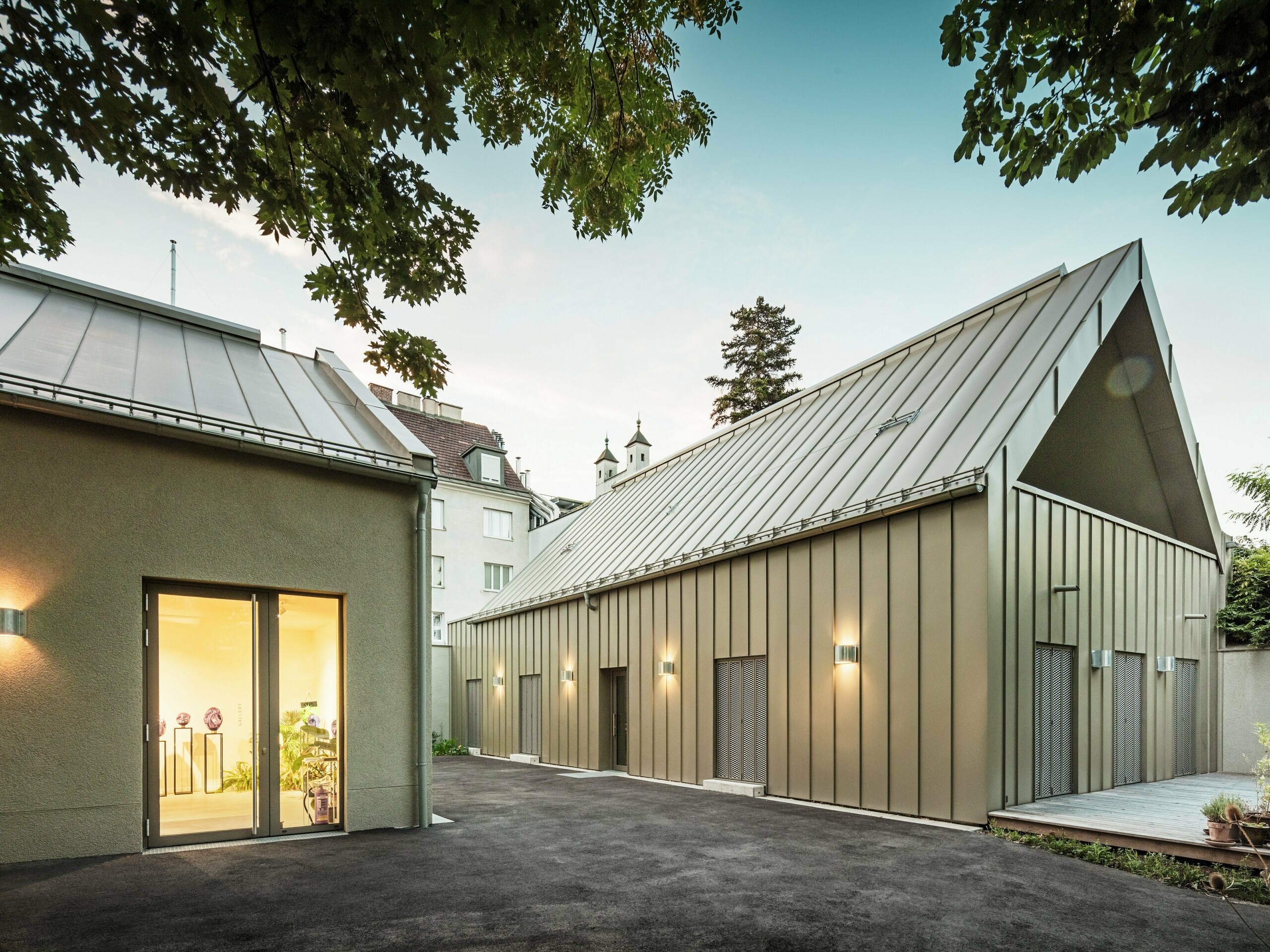 Vue latérale du Studio Comploj à Vienne avec une façade en aluminium PREFALZ en P.10 bronze Prefa. L'ensemble moderne composé d'un atelier de soufflage de verre, d'une galerie et d'un espace de vie allie artisanat et architecture.
