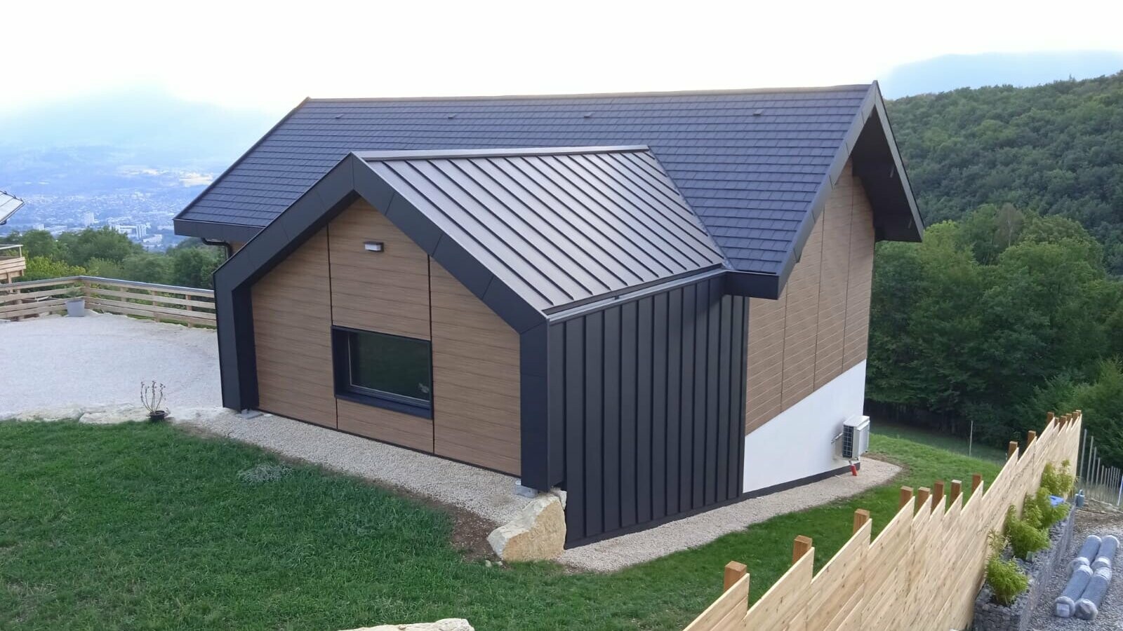 Prise de vue de l'arrière de la maison où on aperçoit la couverture en joint debout Prefalz et les façades en Siding PREFA teinte noyer foncé