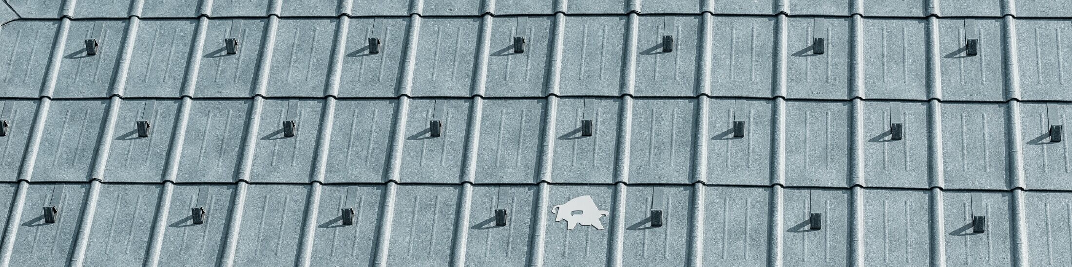 Tuile PREFA avec logo taureau PREFA en P.10 gris pierre ; surface de toit en tôle PREFA ;