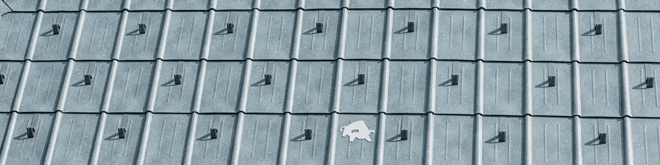 Tuile PREFA avec logo taureau PREFA en P.10 gris pierre ; surface de toit en tôle PREFA ;