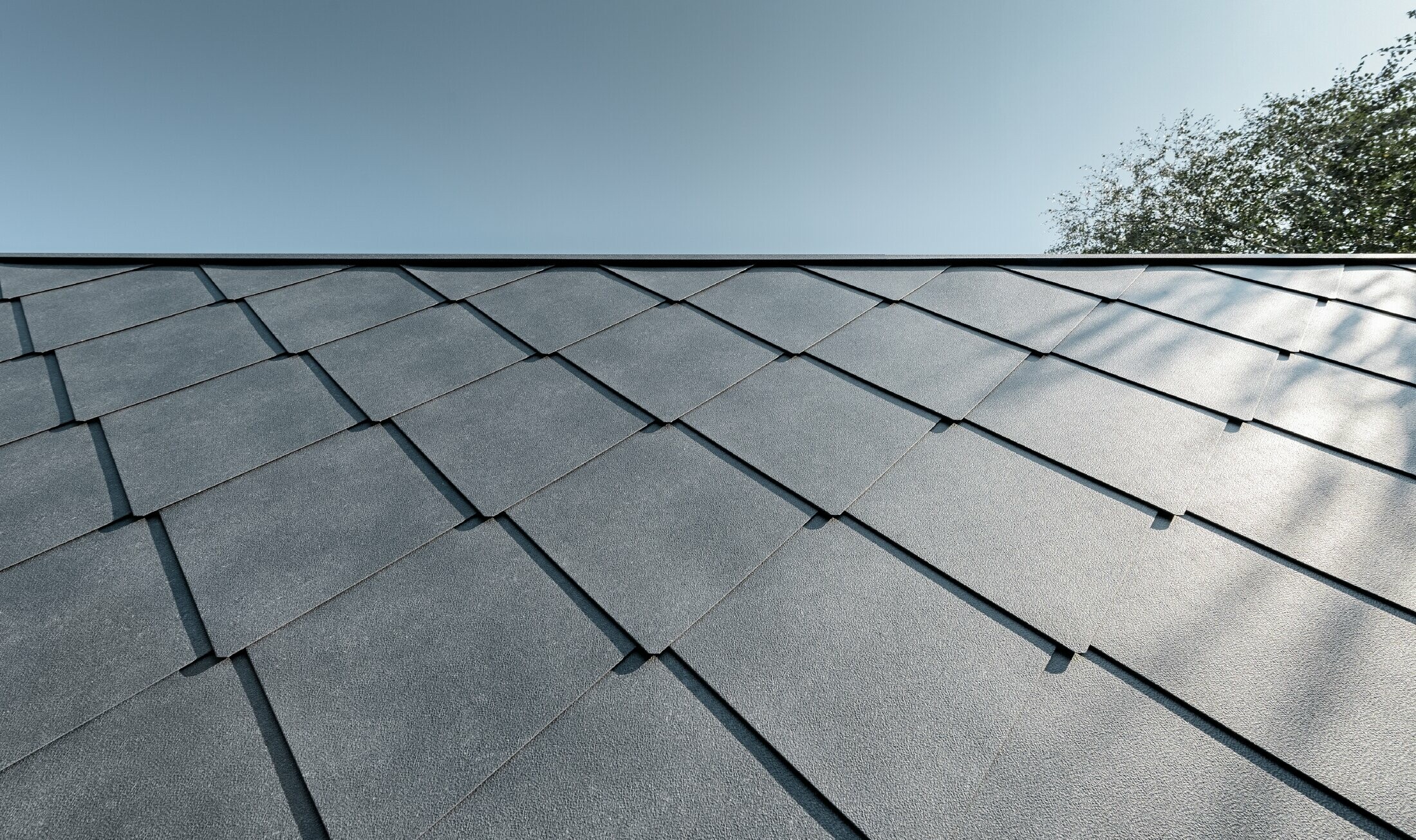 Annexe d’une école primaire — Habillée de losanges de toiture et de façade PREFA en aluminium de couleur gris pierre