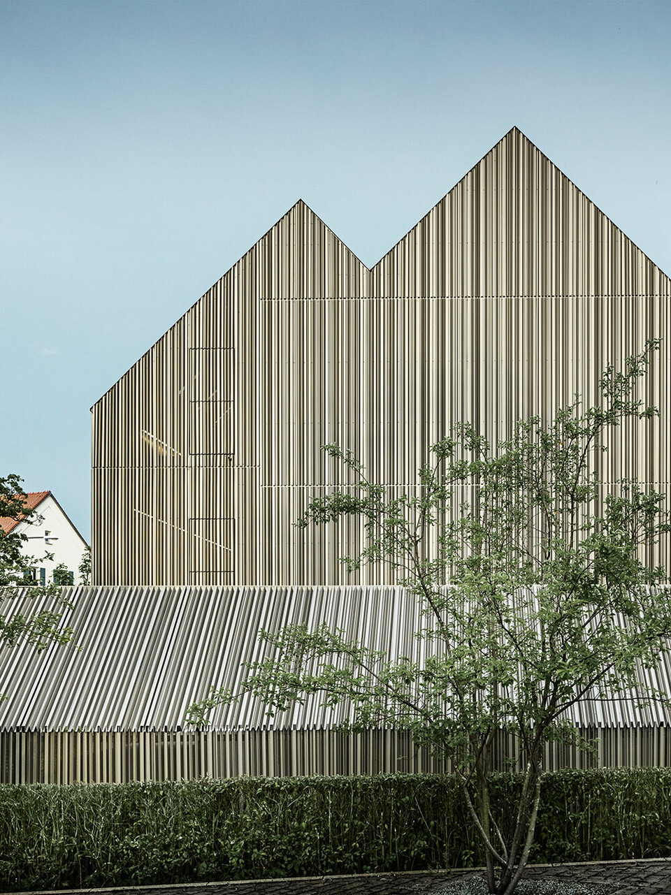 Das Wohnhaus in Dachau vom Büro lynx architecture aus der seitlichen Normalperspektive, umgeben von Grünflächen, Bäumen und Nachbargebäuden.