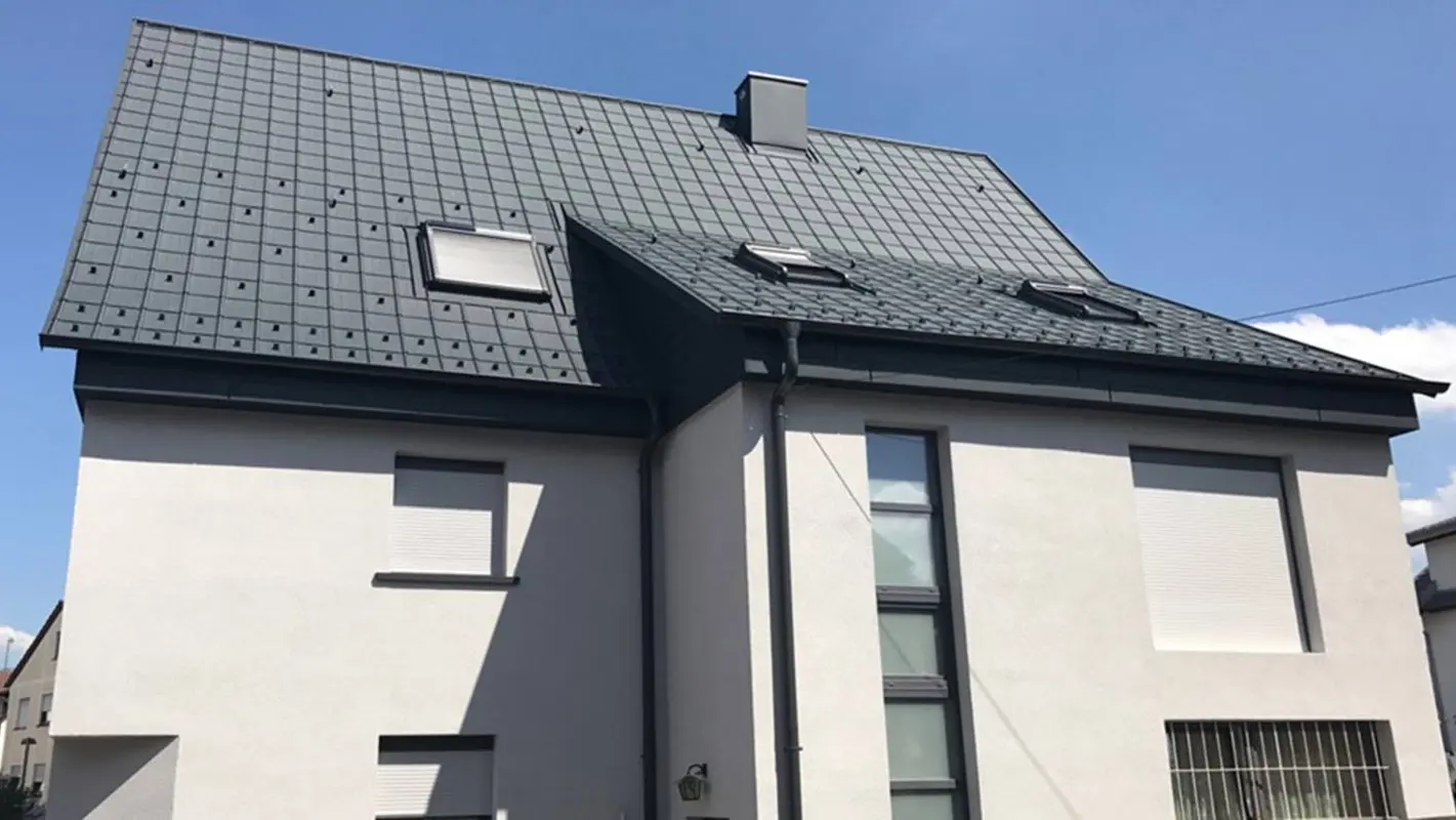 Rénovation d’un toit à deux pans à l’aide de tuiles PREFA, façade blanche