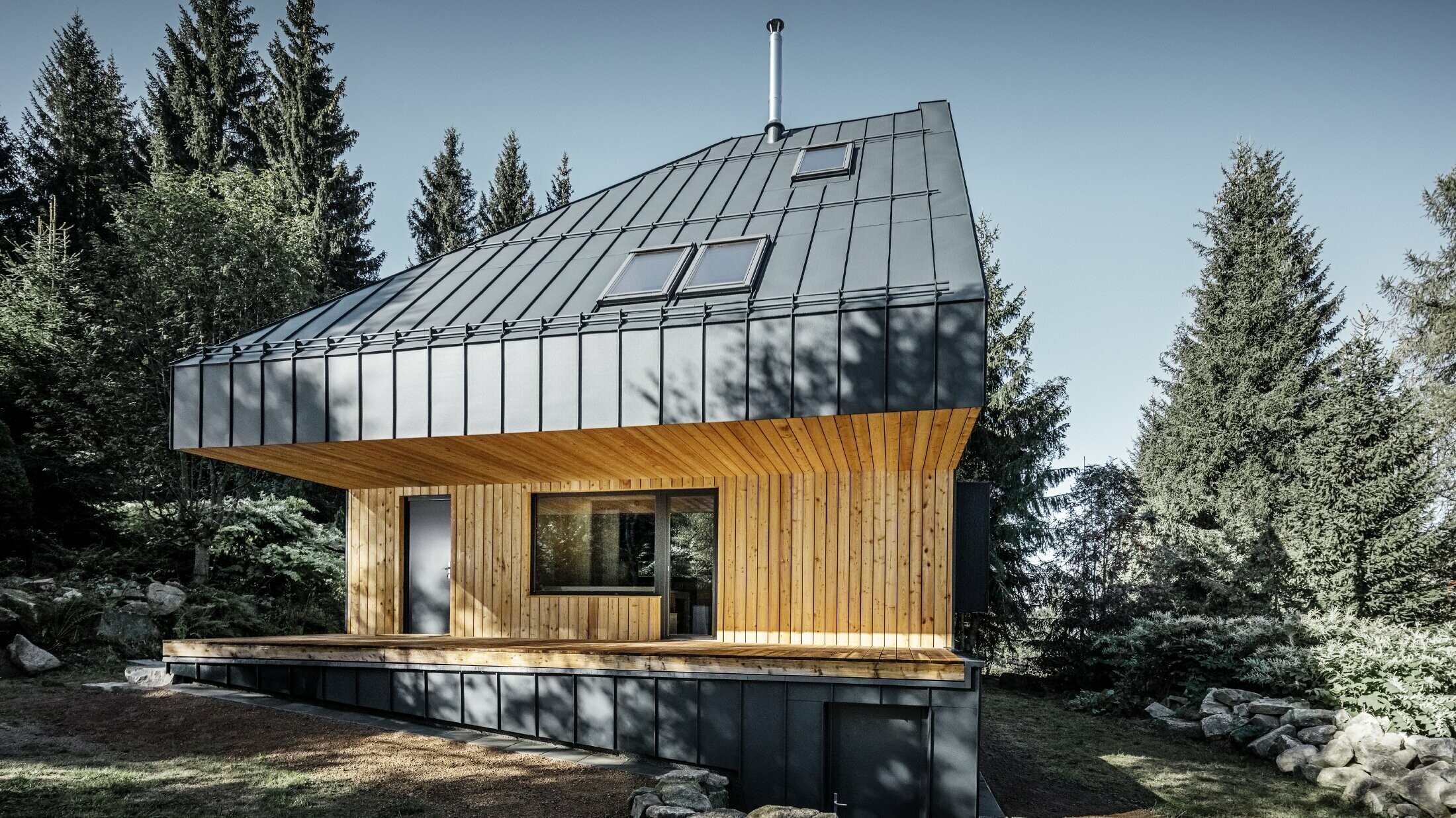 Maison individuelle architecturale en forêt, l'imposante toiture a été habillée de joint debout en aluminium PREFALZ de couleur anthracite. La sous-face ainsi que la façade sont habillées de panneaux en bois.