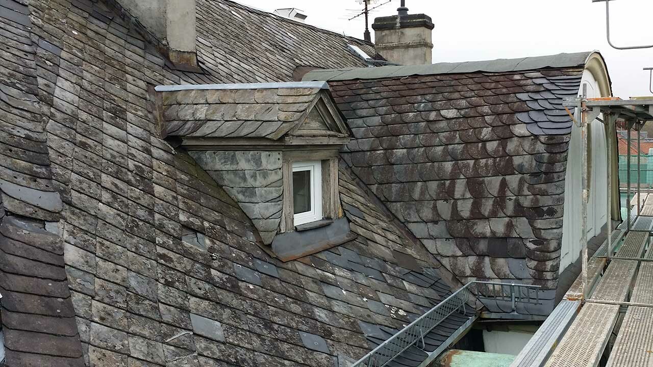 Hôtel à Bad Kissingen avant la rénovation à l’aide de losanges de toiture PREFA. Les éléments de toit sont recouverts de mousse et nécessitent une rénovation importante.