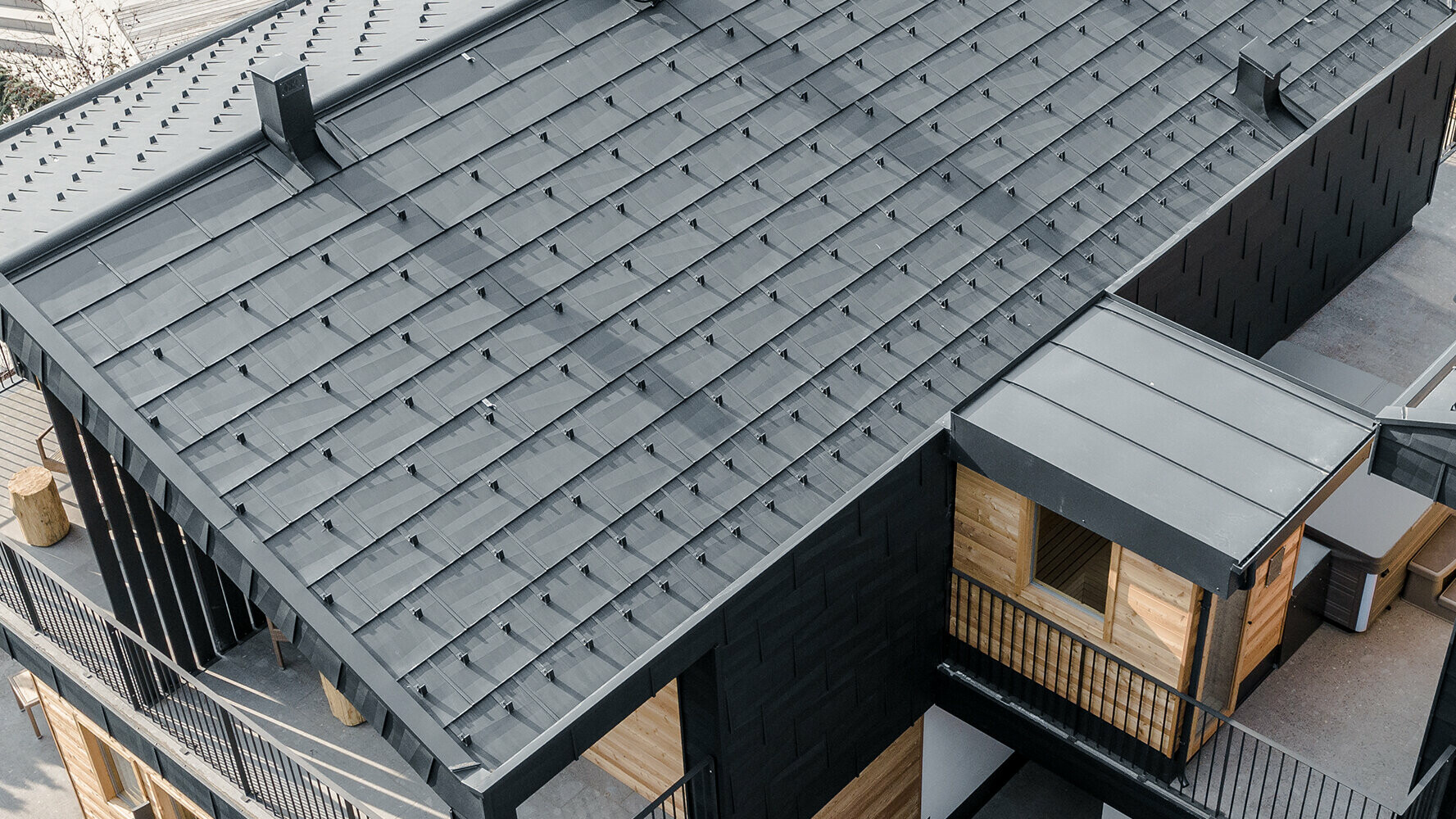 Nouveaux appartements revêtus de panneaux de toit et de façade FX.12 de PREFA en P.10 anthracite et bois.