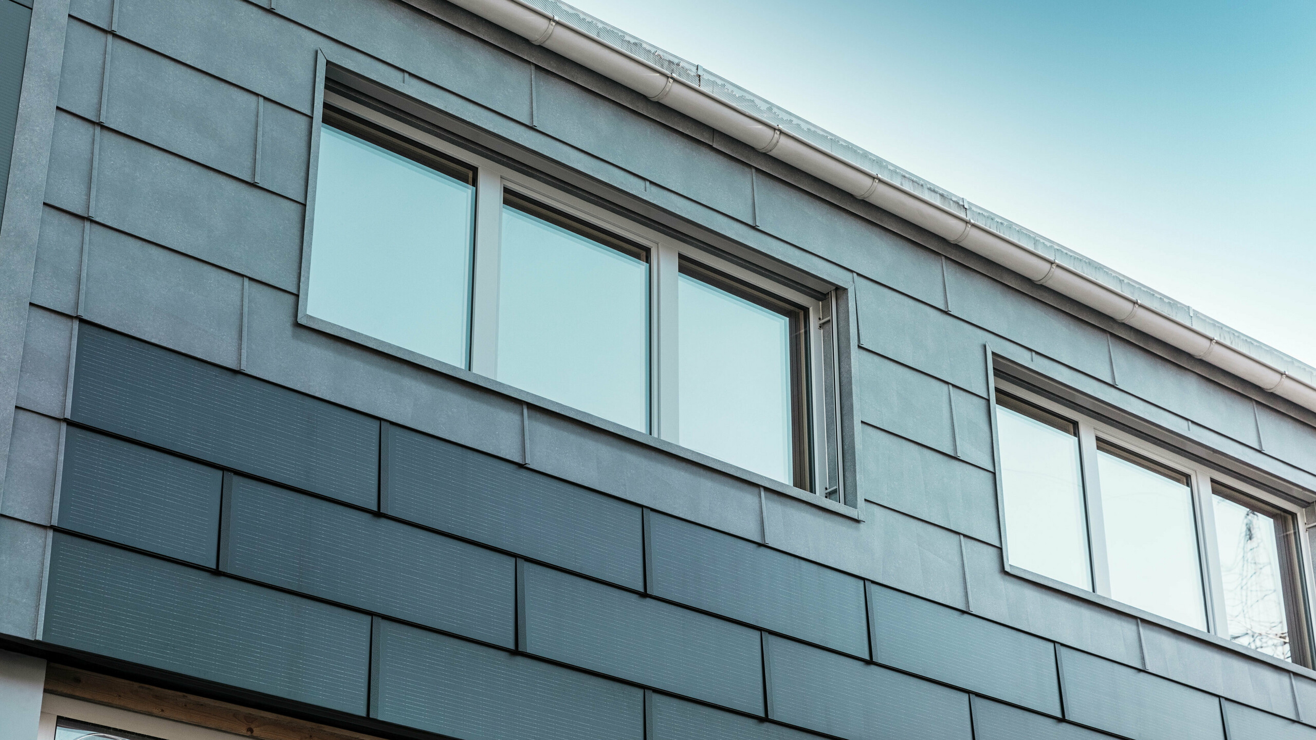 La façade du bâtiment de l'entreprise a été revêtue de tuiles solaires innovantes, combinées aux panneaux de façade FX.12 de PREFA.