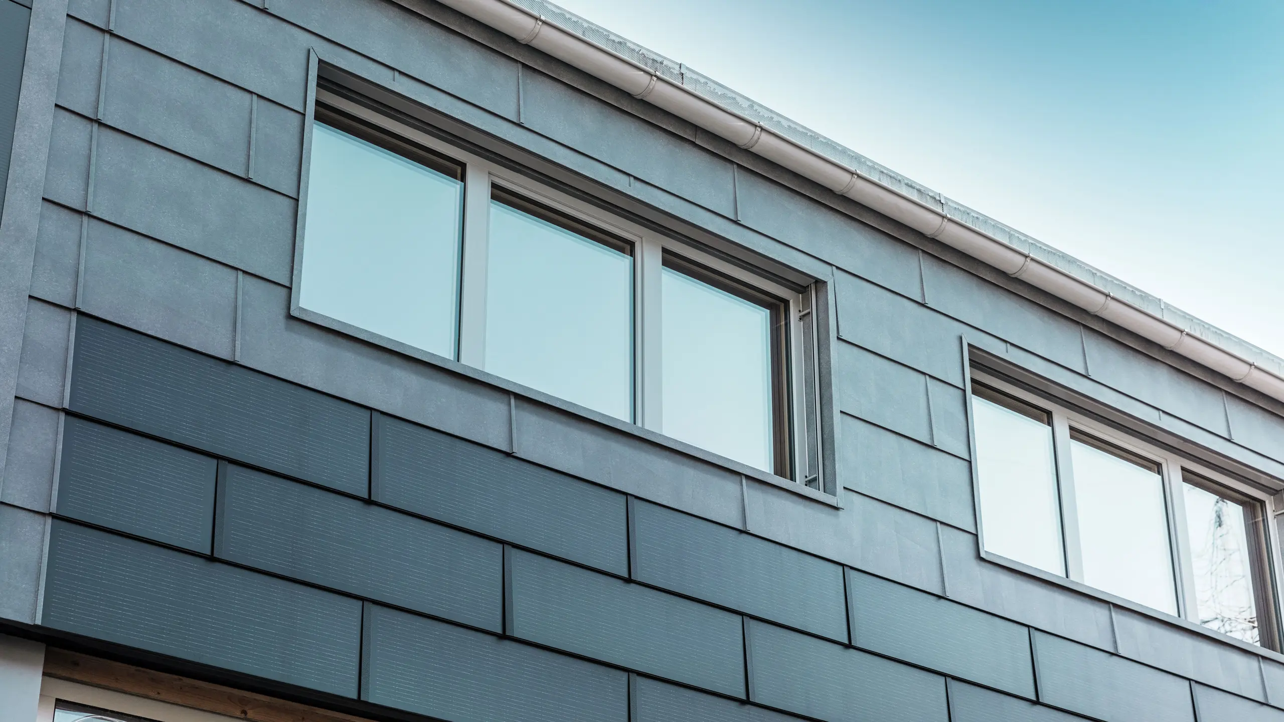 La façade du bâtiment de l'entreprise a été revêtue de tuiles solaires innovantes, combinées aux panneaux de façade FX.12 de PREFA.