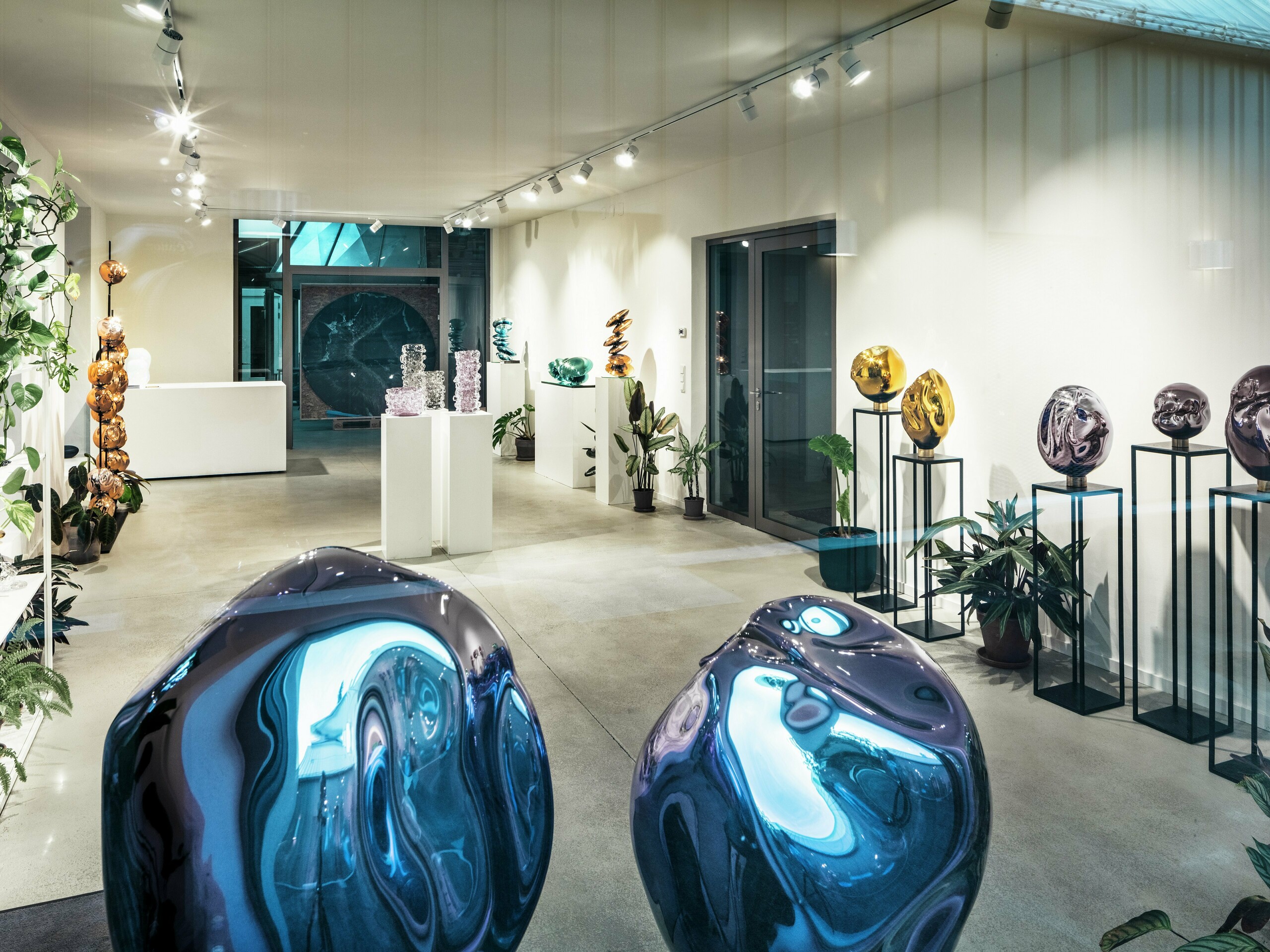 Vue intérieure du Studio Comploj à Vienne avec une exposition d'objets en verre faits à la main. L'espace galerie moderne combine art, design et artisanat dans un environnement élégant.