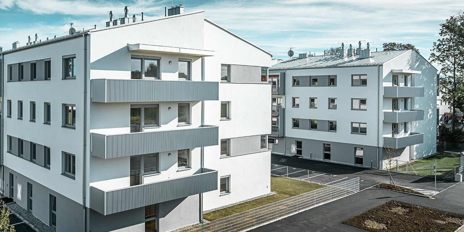 Complexe résidentiel moderne avec façade blanche et balcons en profil triangle  PREFA couleur argent métallisé
