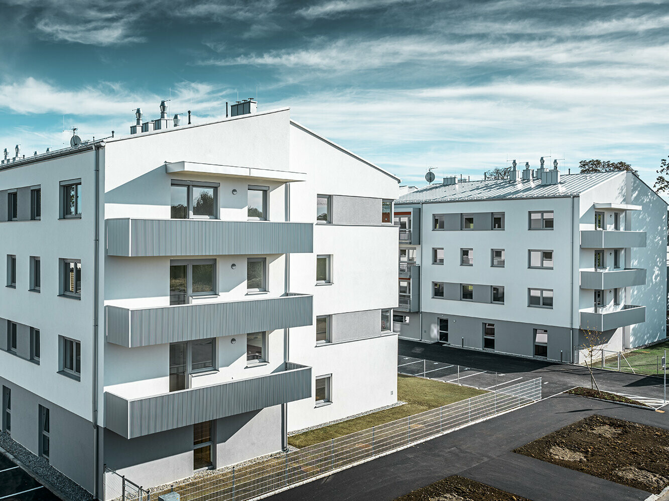 Complexe résidentiel moderne avec façade blanche et balcons en profil triangle PREFA couleur argent métallisé