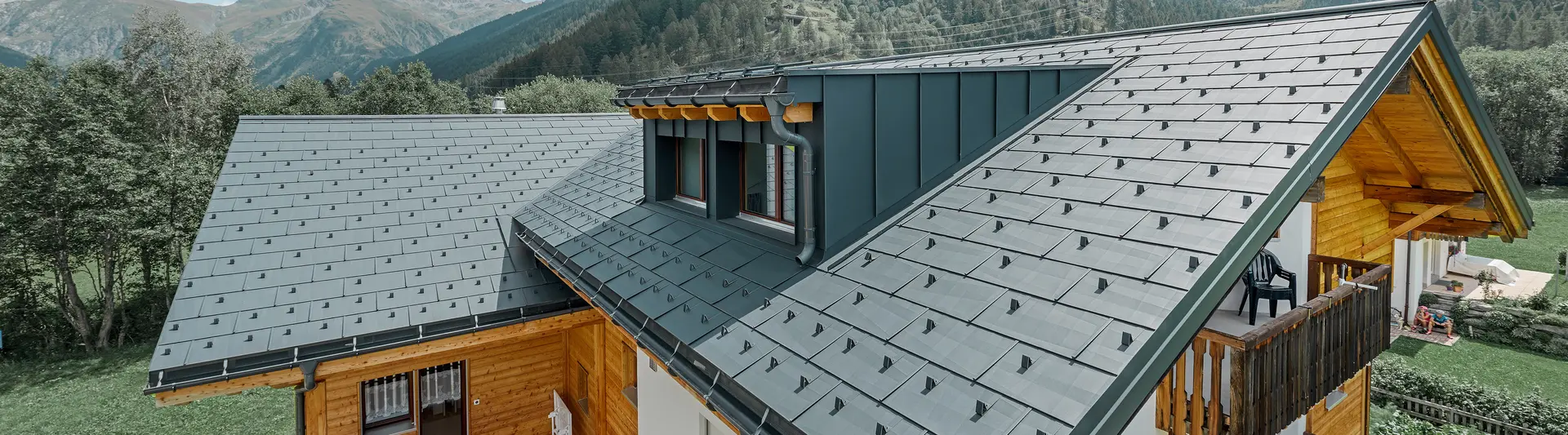 Bâtiment d’habitation rénové avec toit à deux pans et lucarne ; la rénovation de la toiture a été réalisée avec le panneau de toiture FX.12 PREFA couleur anthracite.