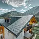 Bâtiment d’habitation rénové avec toit à deux pans et lucarne ; la rénovation de la toiture a été réalisée avec le panneau de toiture FX.12 PREFA couleur anthracite.