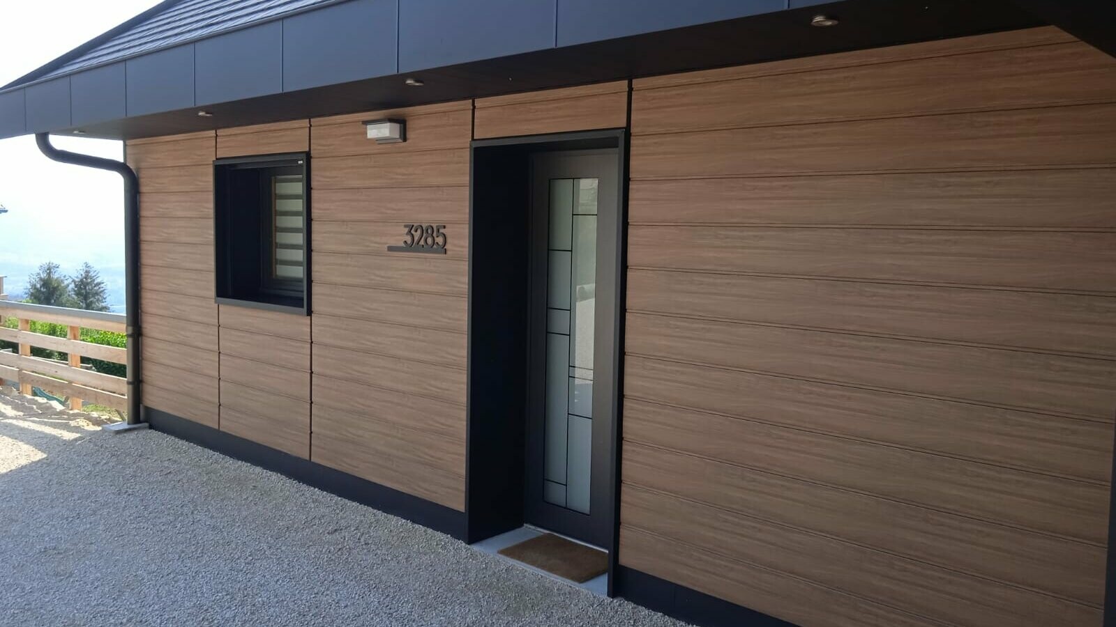 Vue rapprochée du côté de cette maison individuelle réalisée en Siding PREFA dans la teinte imitation bois noyer foncé.