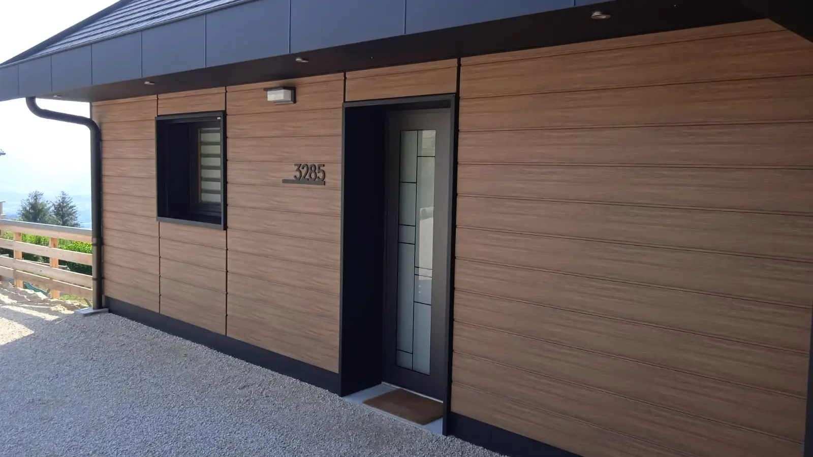 Vue rapprochée du côté de cette maison individuelle réalisée en Siding PREFA dans la teinte imitation bois noyer foncé.