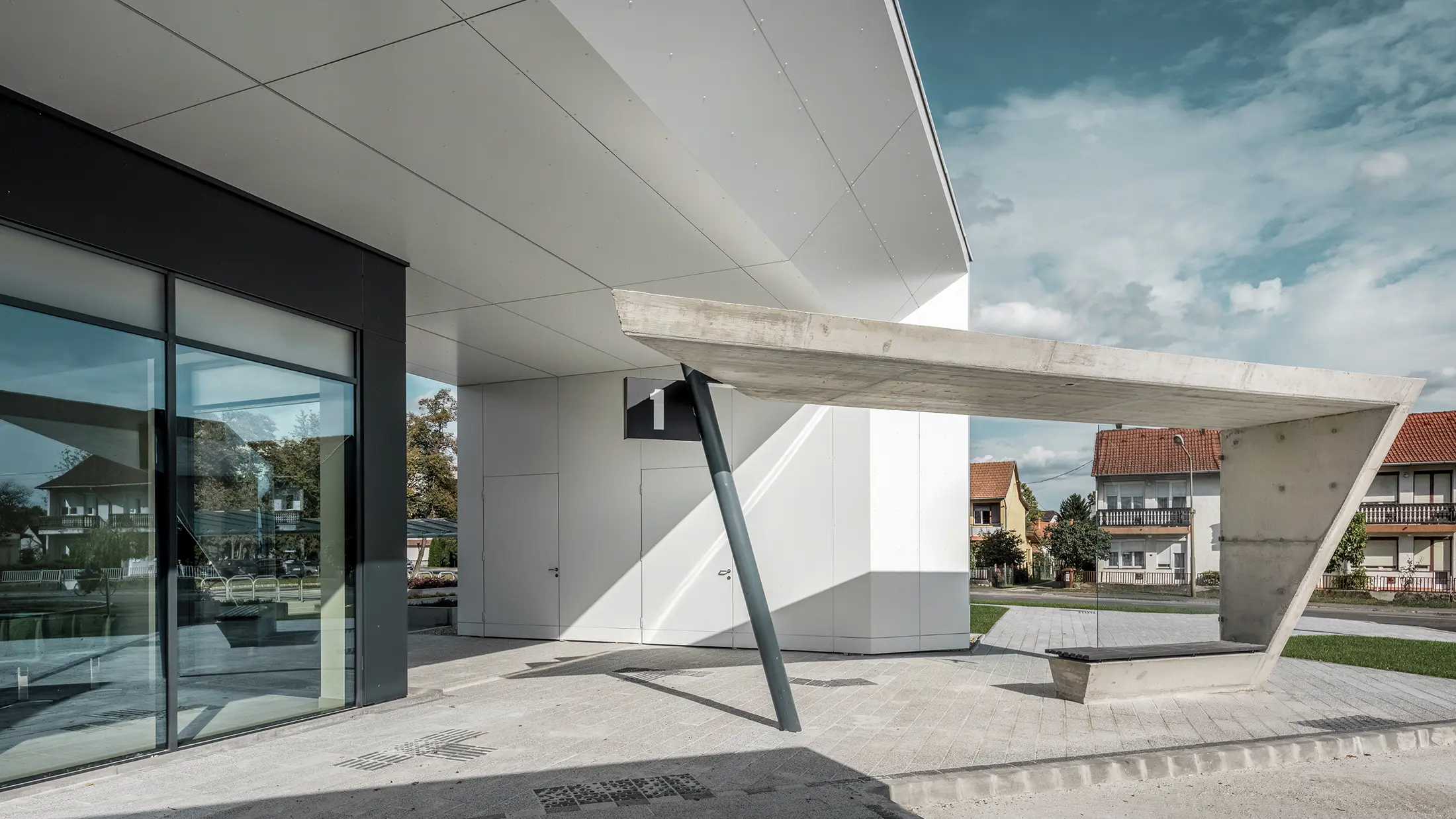 Entrée de la gare routière de Lenti ; la sous-face de la toiture est revêtue de panneaux composites en aluminium PREFABOND de PREFA en blanc pur, tandis que les éléments de façade au niveau des portes d'entrée et des vitrines sont revêtus de P.10 blanc pur.