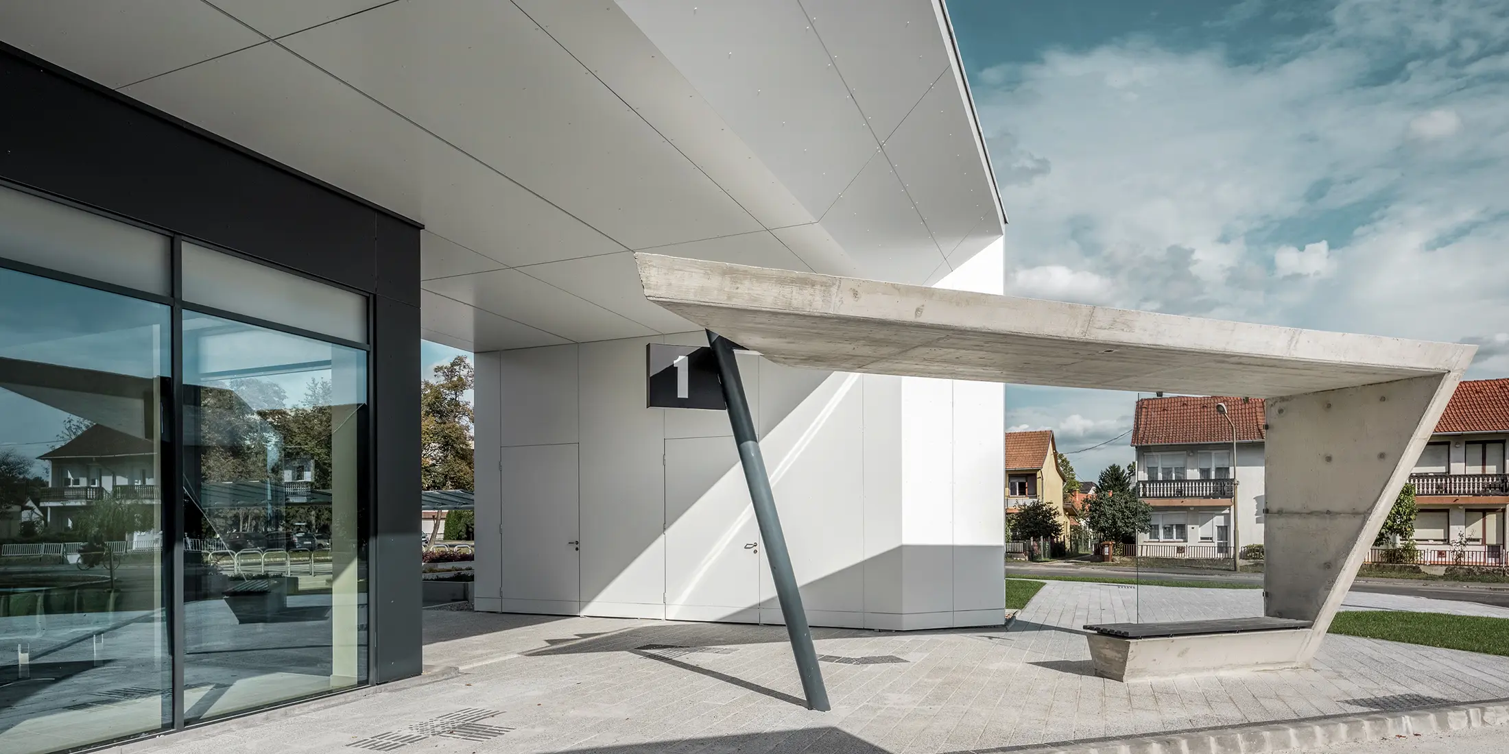 Entrée de la gare routière de Lenti ; la sous-face de la toiture est revêtue de panneaux composites en aluminium PREFABOND de PREFA en blanc pur, tandis que les éléments de façade au niveau des portes d'entrée et des vitrines sont revêtus de P.10 blanc pur.