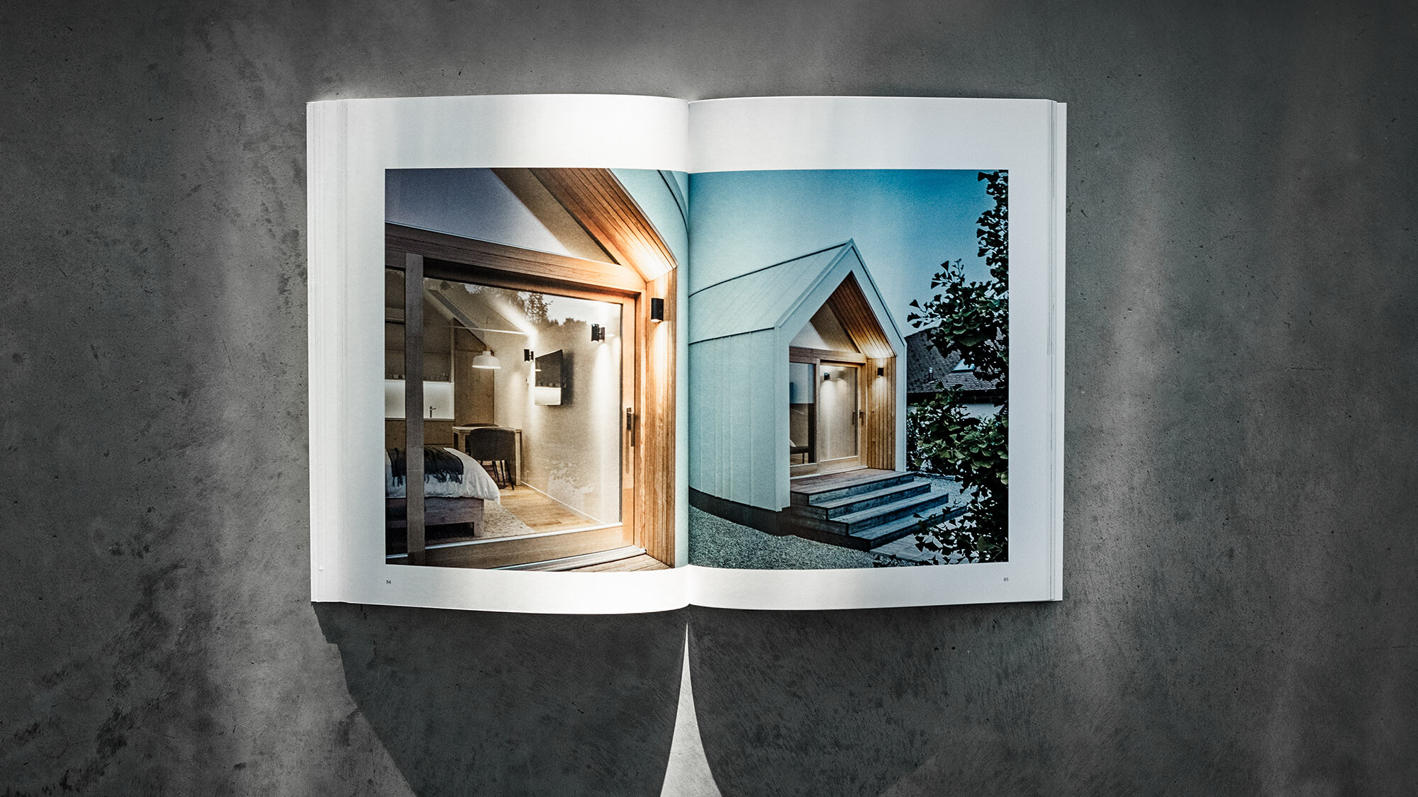Le livre PREFARENZEN 2024 ouvert et sur fond gris avec une double page illustrant les constructions modulaires de kubico domino arhitekti.