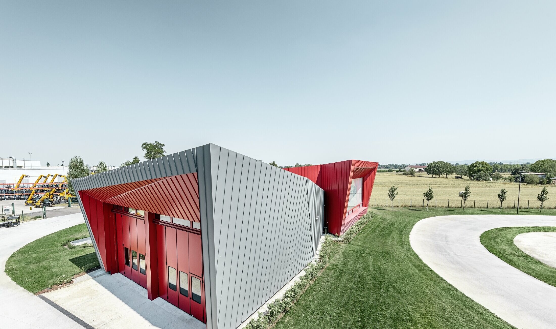 Centre d’entraînement moderne Dieci à Montecchio Emilia (Italie) — Façade des tribunes en aluminium réalisée avec des bandes Prefalz gris souris et Falzonal rouge carmin