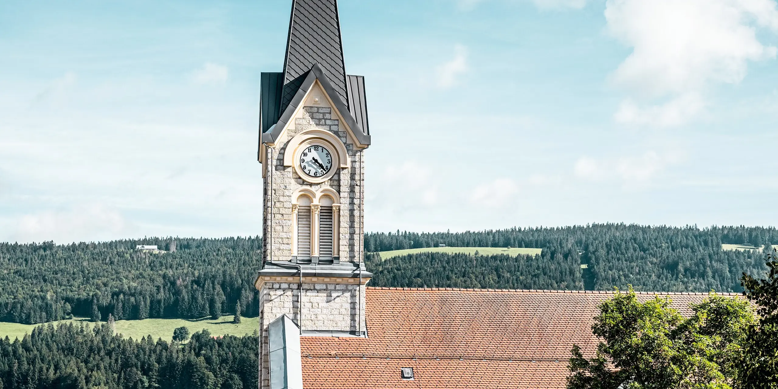 L'église rénovée du Sentier s'intègre harmonieusement dans le vaste paysage vallonné suisse. L'accroche-regard est la flèche imposante avec les losanges de toiture PREFA 29 × 29 en P.10 gris sombre, qui confèrent au bâtiment historique une structure élégante et précise. Le revêtement en aluminium durable impressionne par sa haute résistance aux intempéries, son faible poids et son adaptation optimale aux géométries de tours exigeantes.