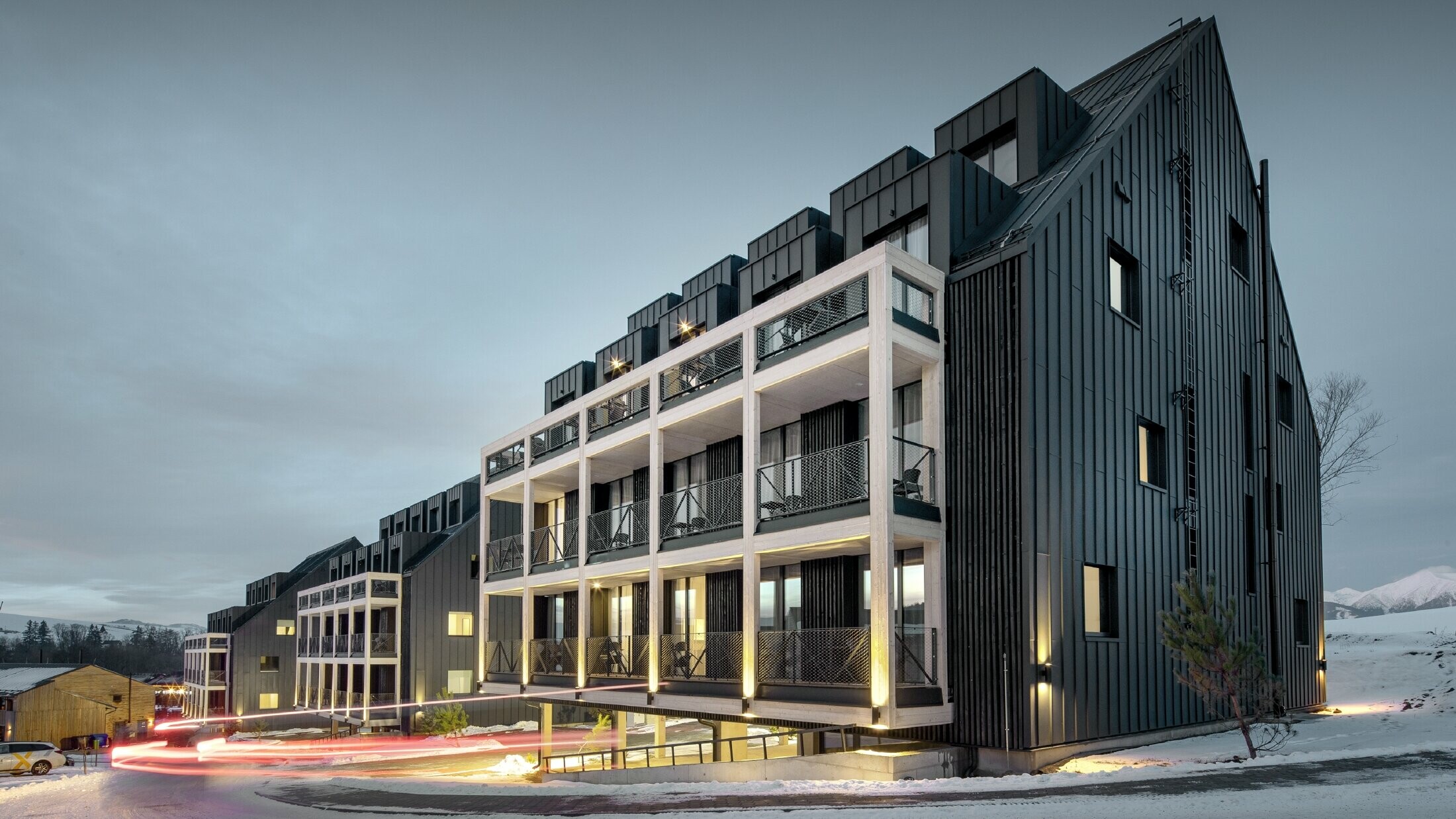 Bâtiments de station de ski en Slovaquie avec balcons et lucarnes, les façades sont habillées de Prefalz couleur anthracite, tout comme le toit à deux versants, environnement enneigé