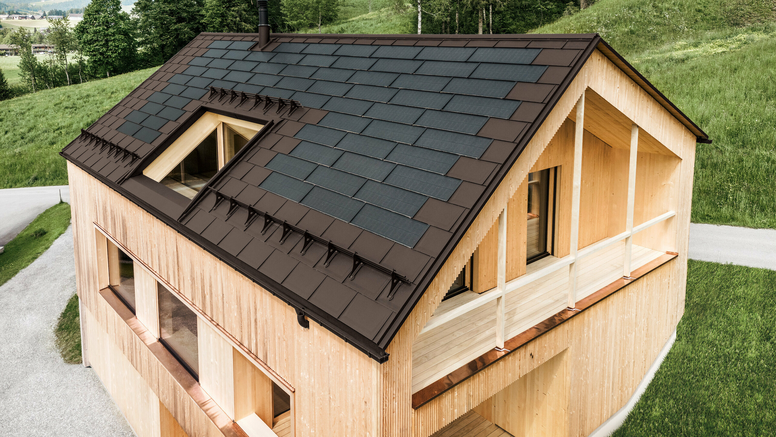 Maison individuelle dans la localité autrichienne d'Egg avec le panneau solaire de toiture PREFA et le panneau de toiture R.16 en brun noisette, combinés à une façade en bois