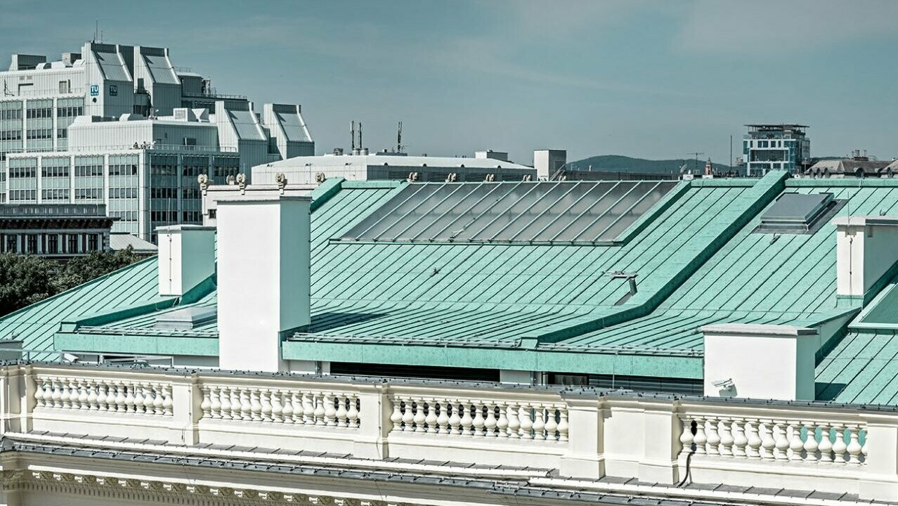 Nahaufnahme des Prefalz-Daches in P.10 patinagrün. Im Hintergrund ist die Technische Universität Wien zu sehen.