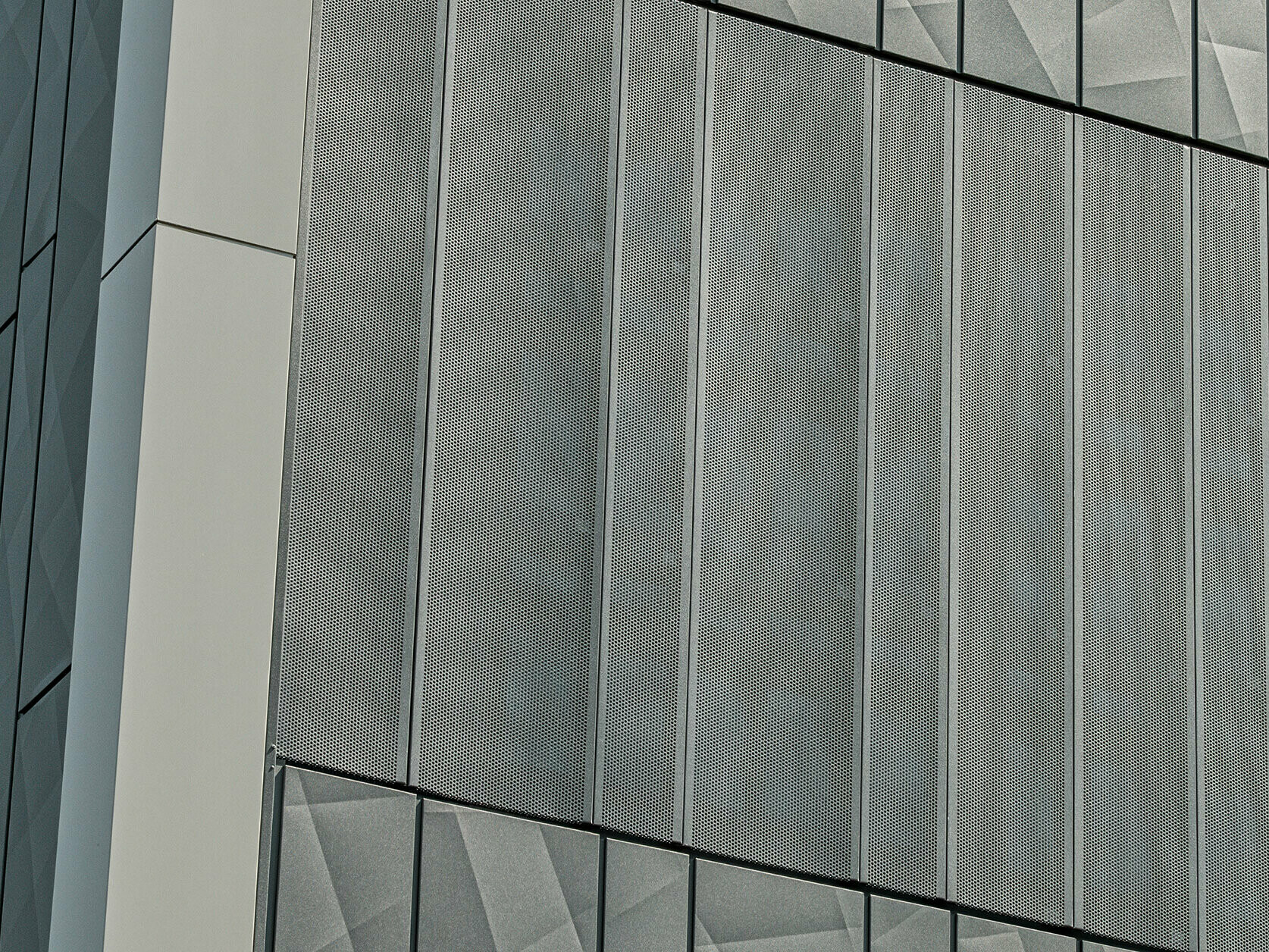 Vue de la façade d'un magasin Eurospar à Rohrbach avec des bardages PREFA Siding.X et des bardages perforés de couleur anthracite. Les éléments Siding.X présentent un motif de joints géométrique vivant, tandis que les bardages perforés offrent une structure moderne et perméable à l'air.