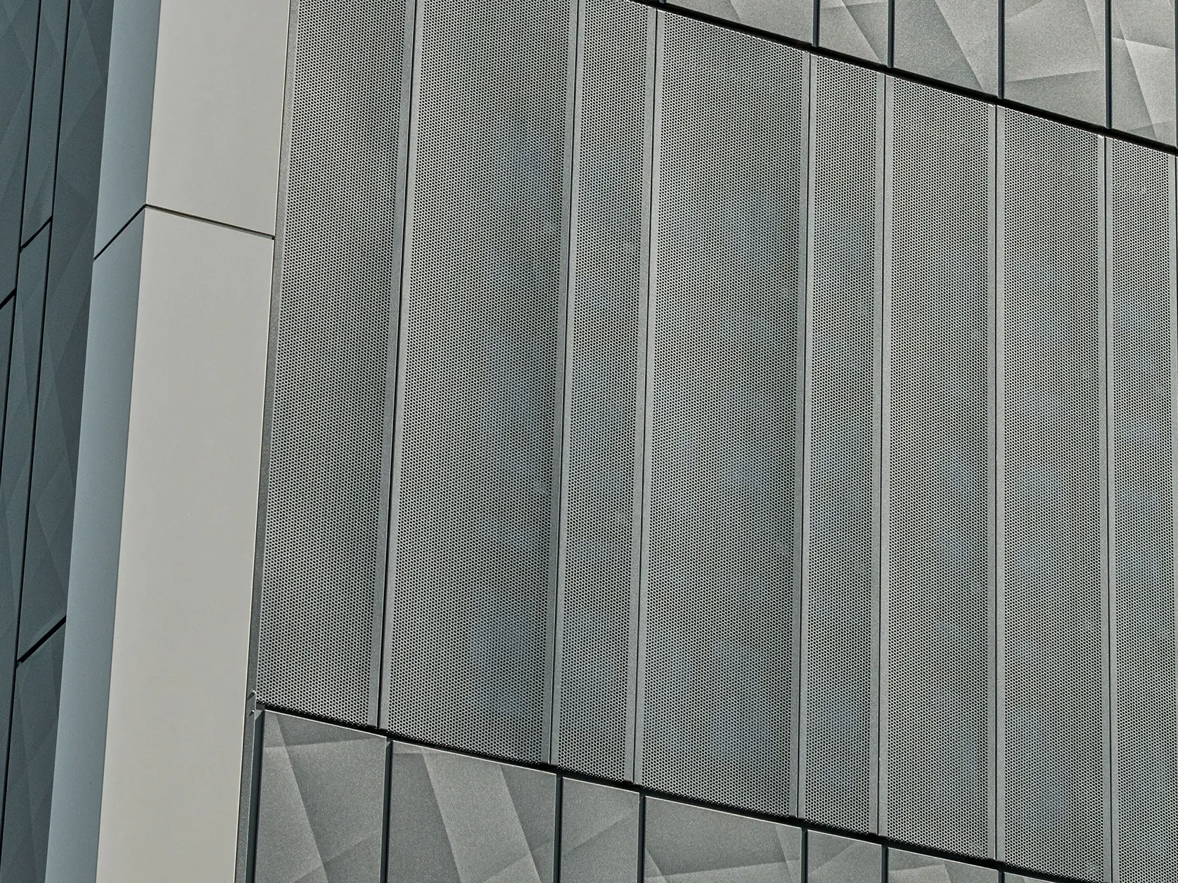 Vue de la façade d'un magasin Eurospar à Rohrbach avec des bardages PREFA Siding.X et des bardages perforés de couleur anthracite. Les éléments Siding.X présentent un motif de joints géométrique vivant, tandis que les bardages perforés offrent une structure moderne et perméable à l'air.