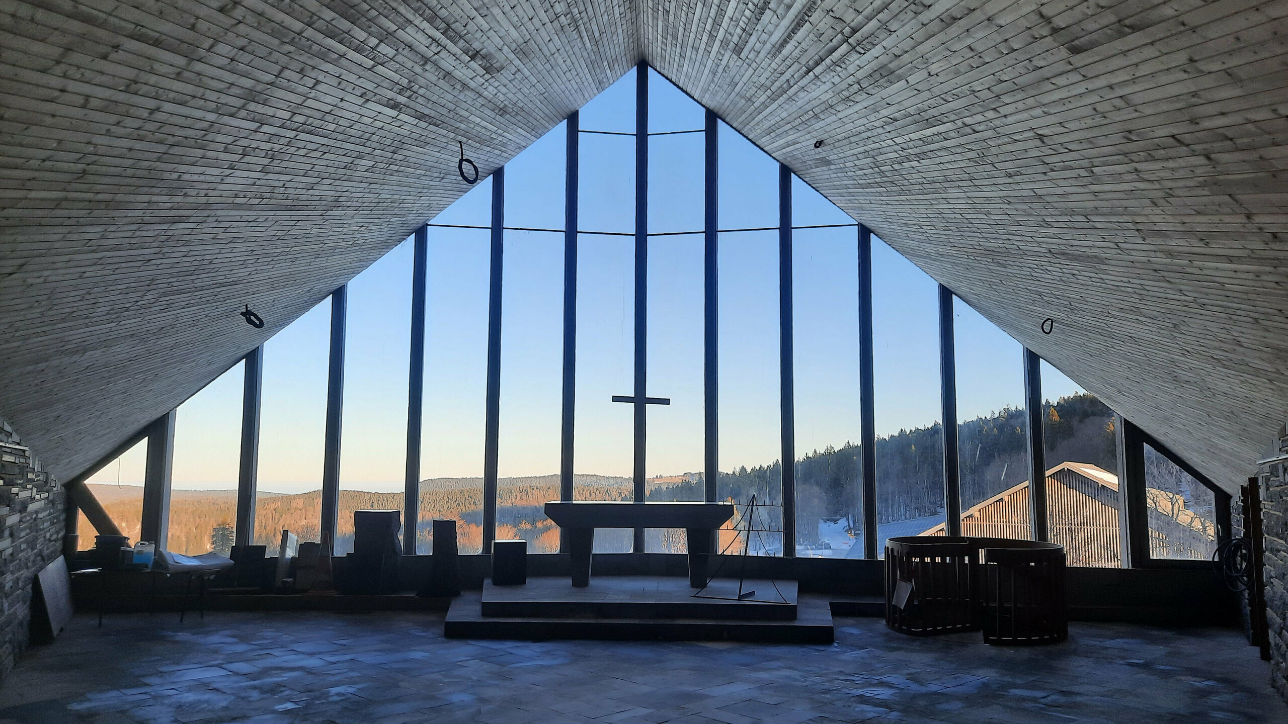 Prise de vue intérieure de la chapelle du Col de la Schlucht où on aperçoit l'hôtel et une croix.