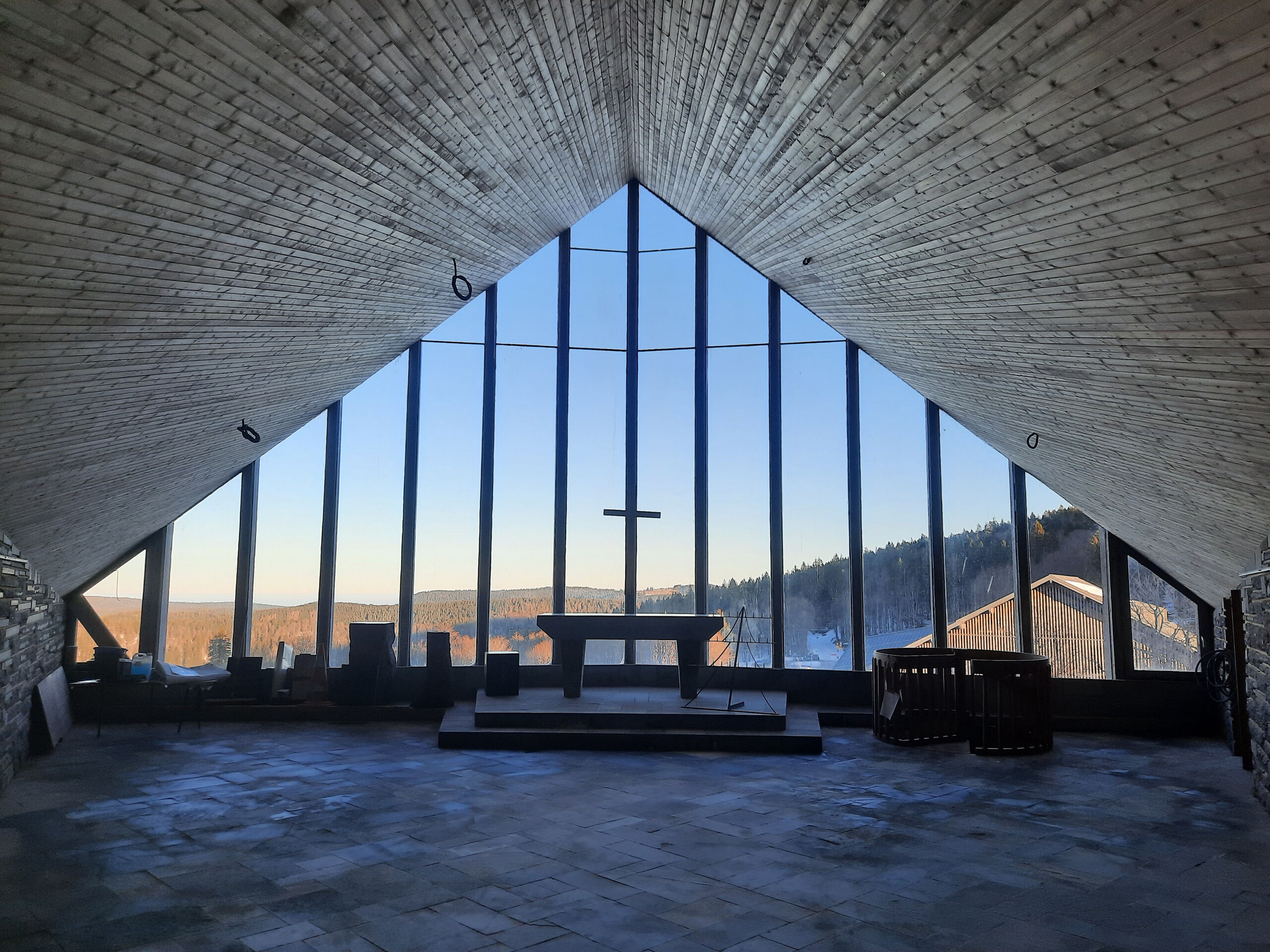 Prise de vue intérieure de la chapelle du Col de la Schlucht où on aperçoit l'hôtel et une croix.